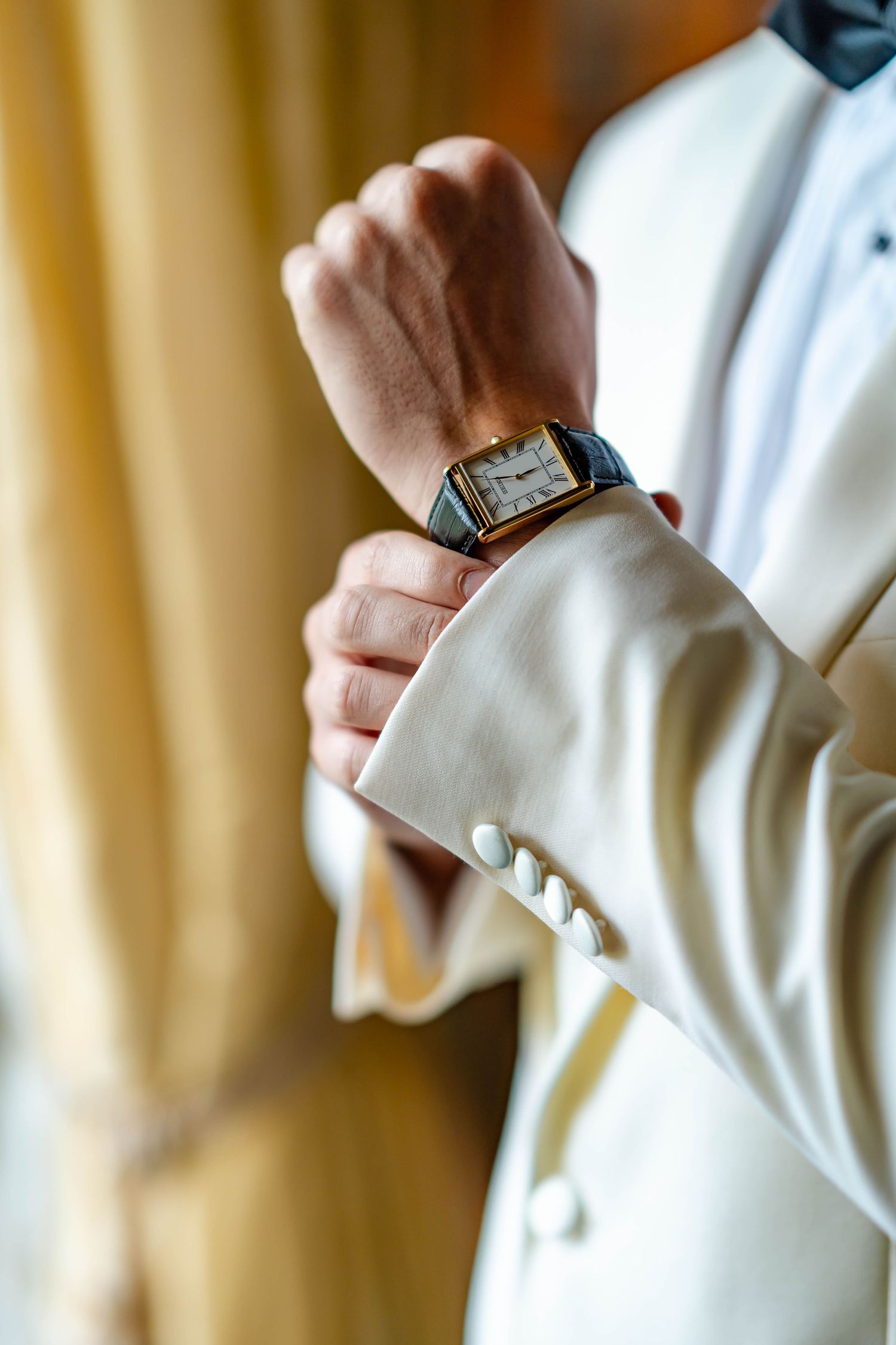 Close-up view of hands adjusting white dress shirt cuffs and sleeve buttons.