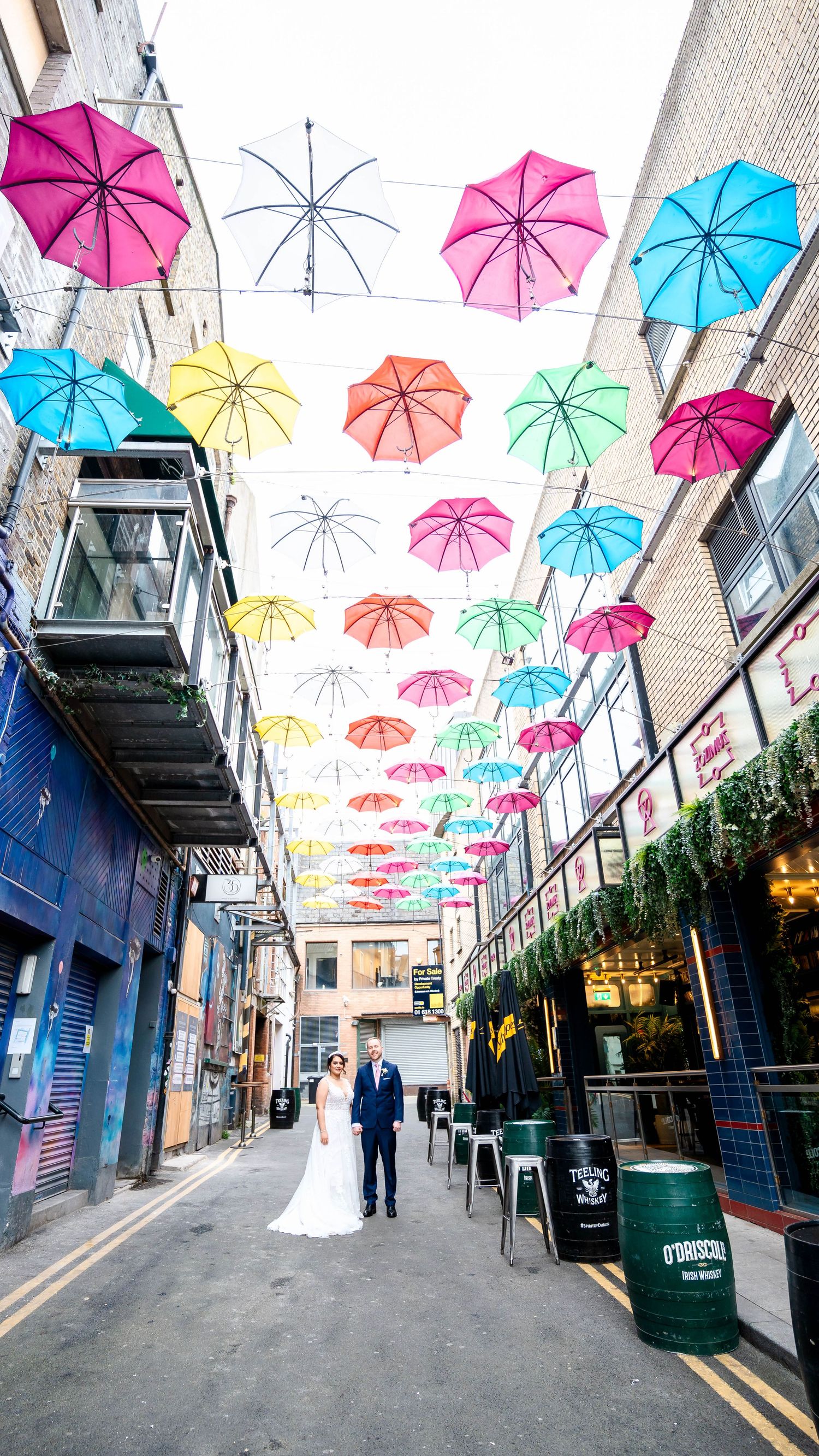 A charming alley decorated with colorful suspended umbrellas creating a whimsical canopy overhead.