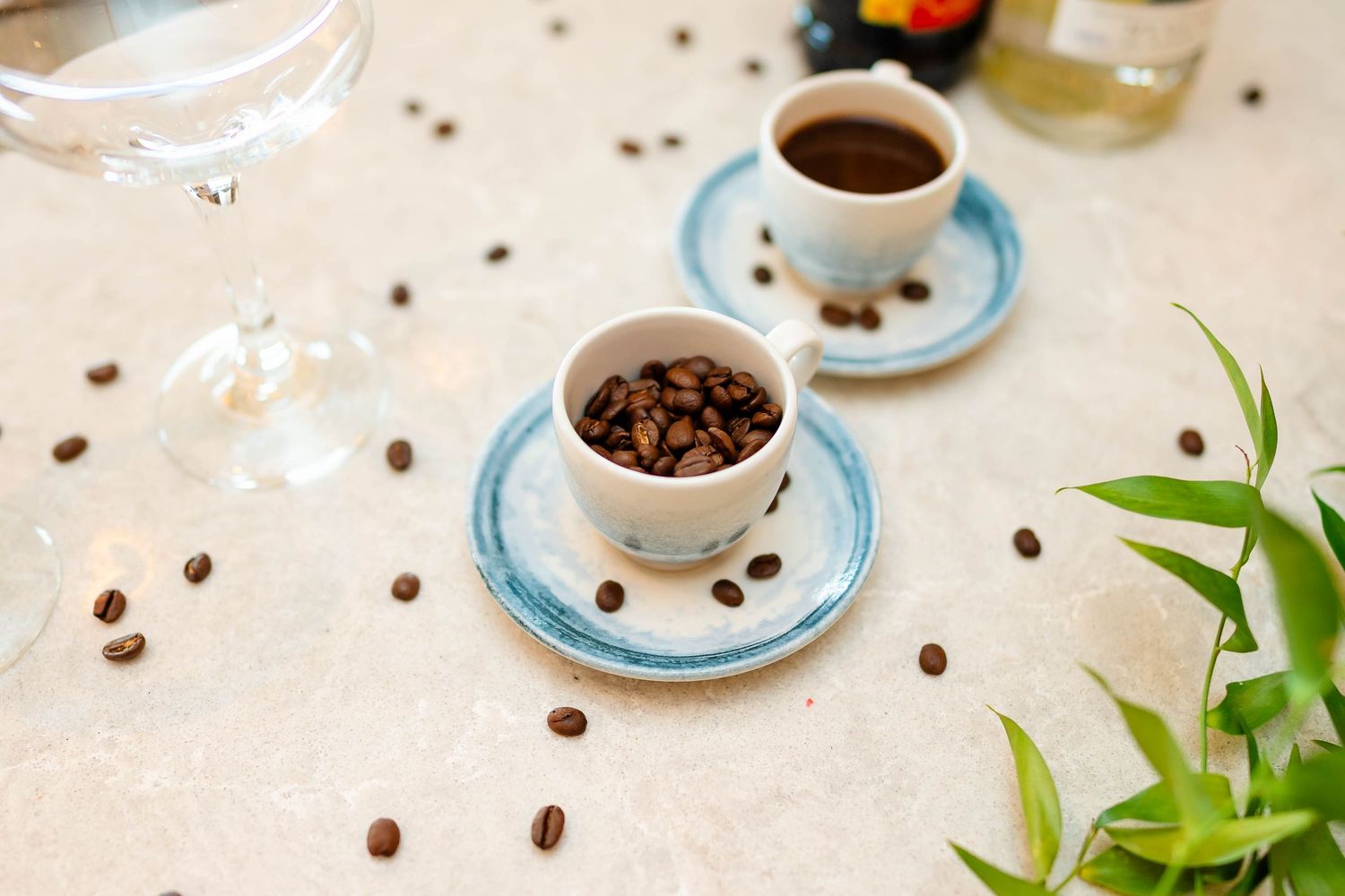 Coffee cups and scattered coffee beans arranged on light colored saucers.