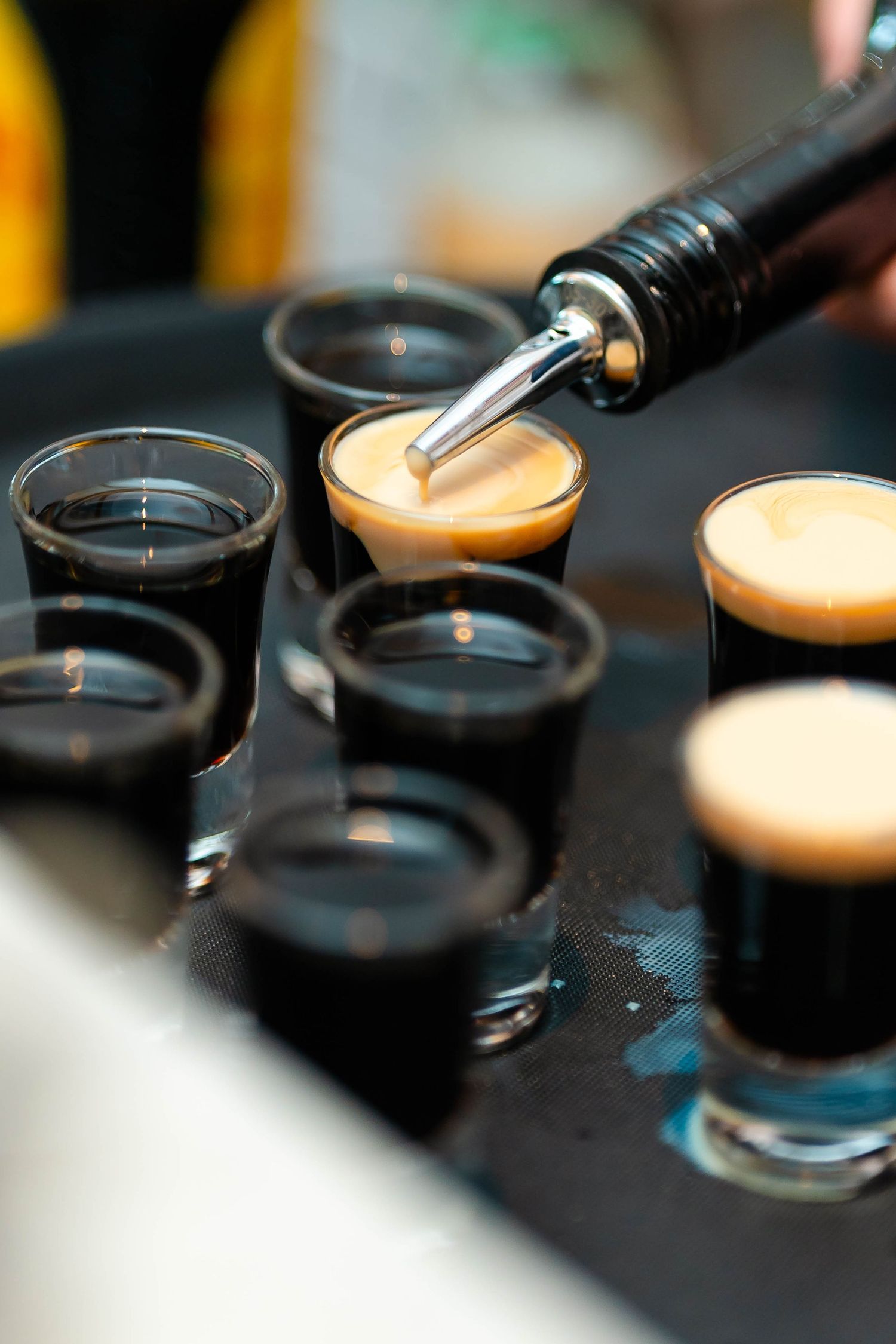 Close-up shots of colorful cocktail drinks being poured in dark ambient lighting.