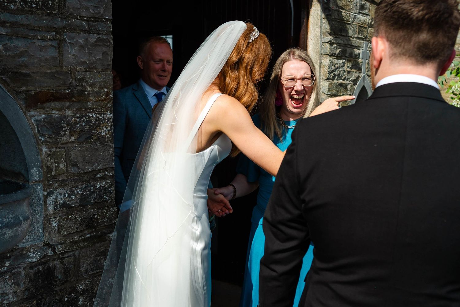 Candid celebration moment between newlyweds and guests outside historic venue.