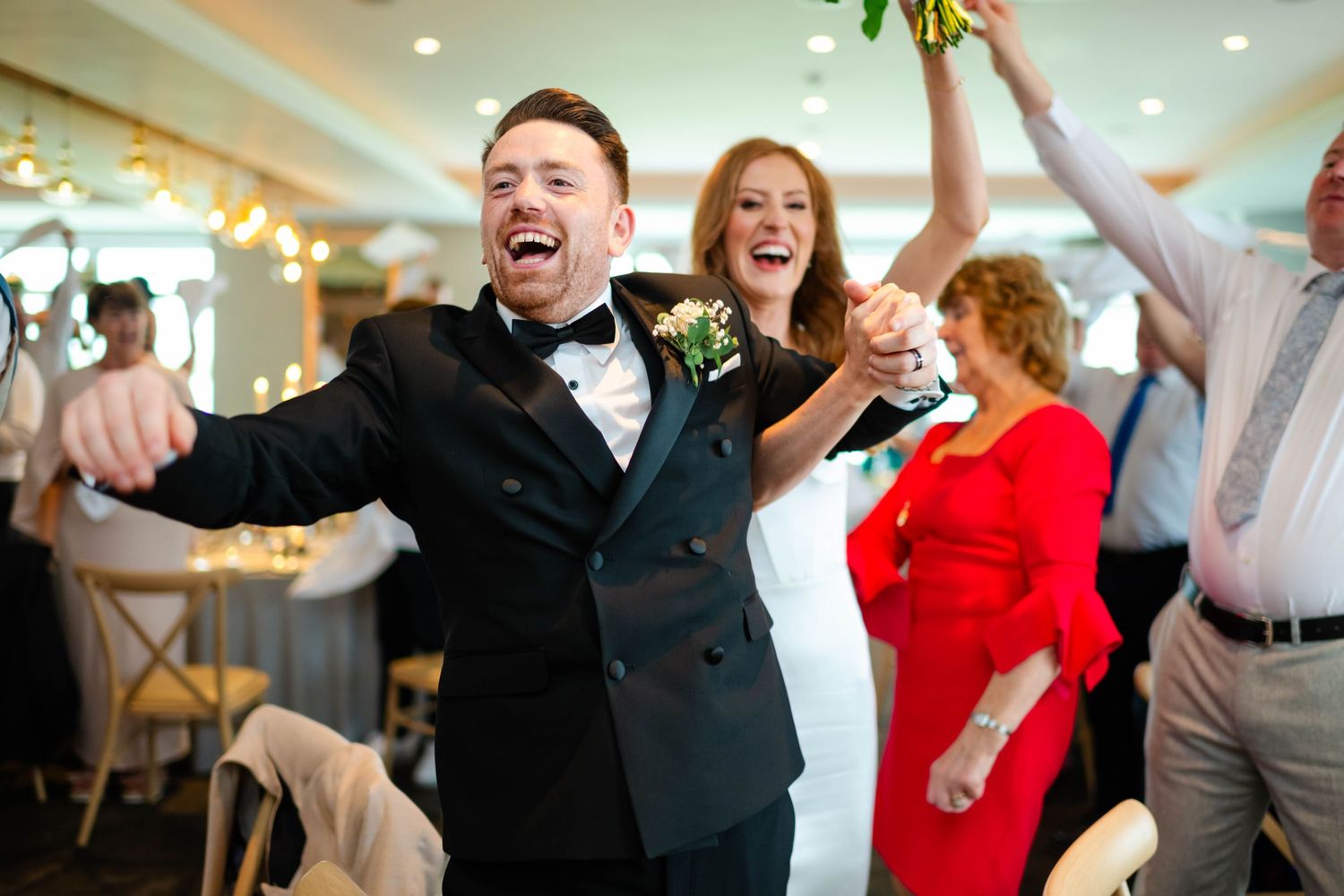 Wedding party celebrating with laughter and joy at an indoor reception.