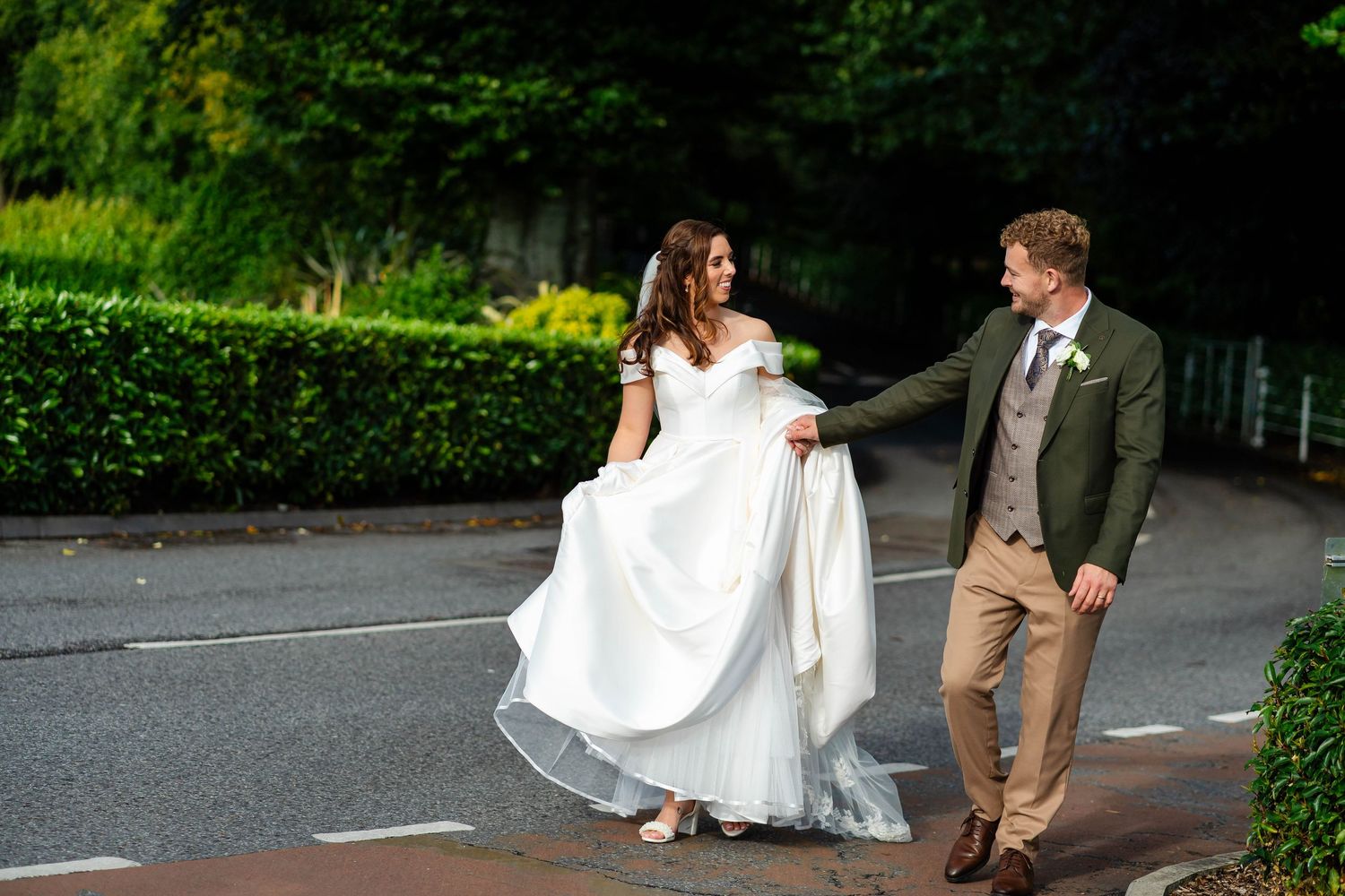 Couple walks playfully together on paved path surrounded by greenery.