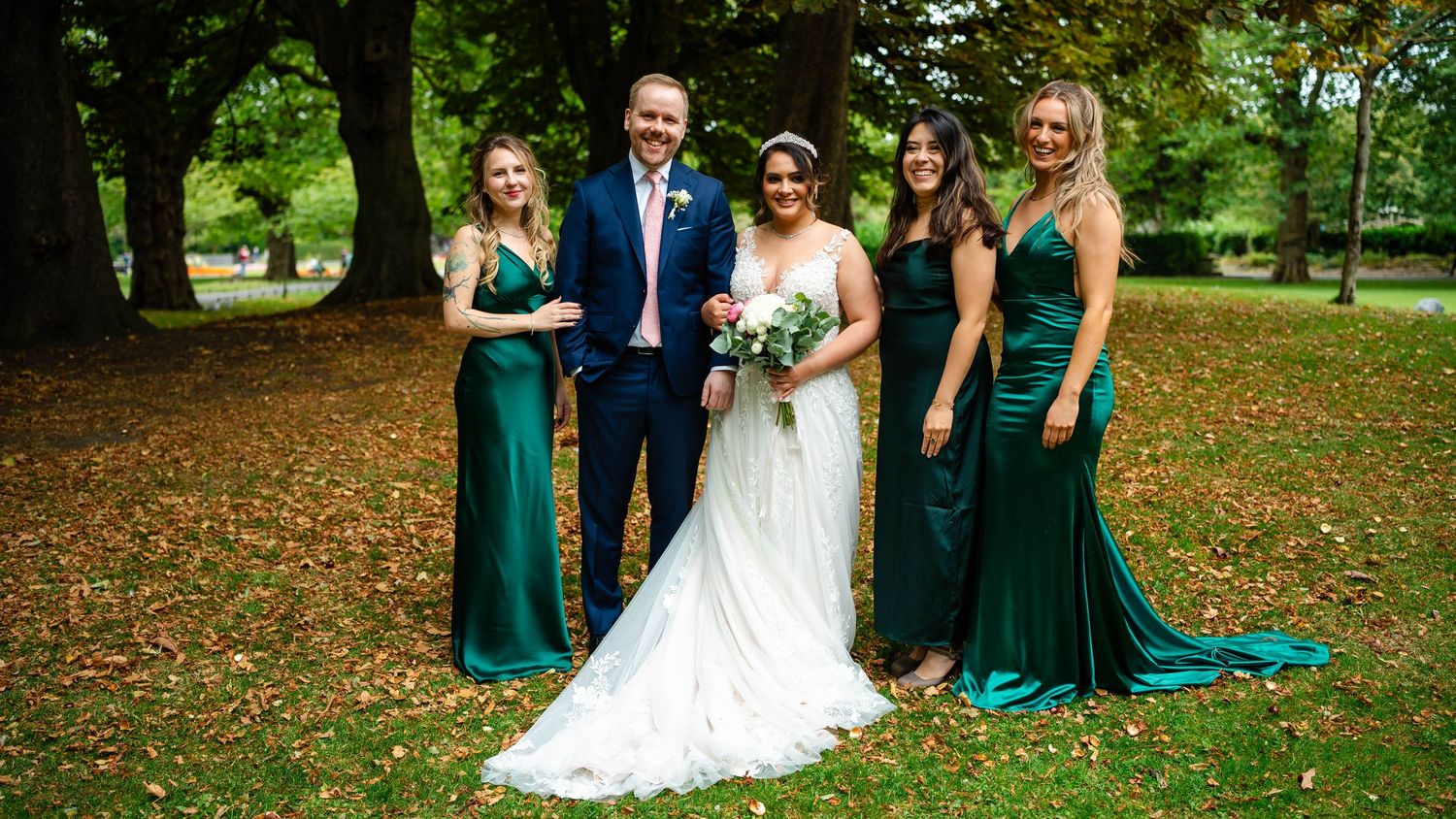 A wedding party poses together outdoors on a beautiful autumn day.