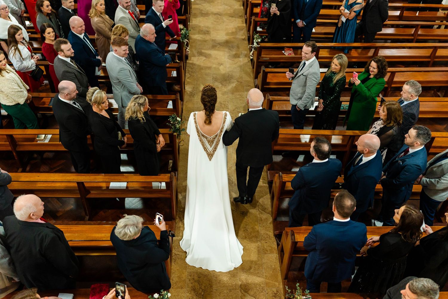 Wedding ceremony in a church with guests standing in wooden pews.