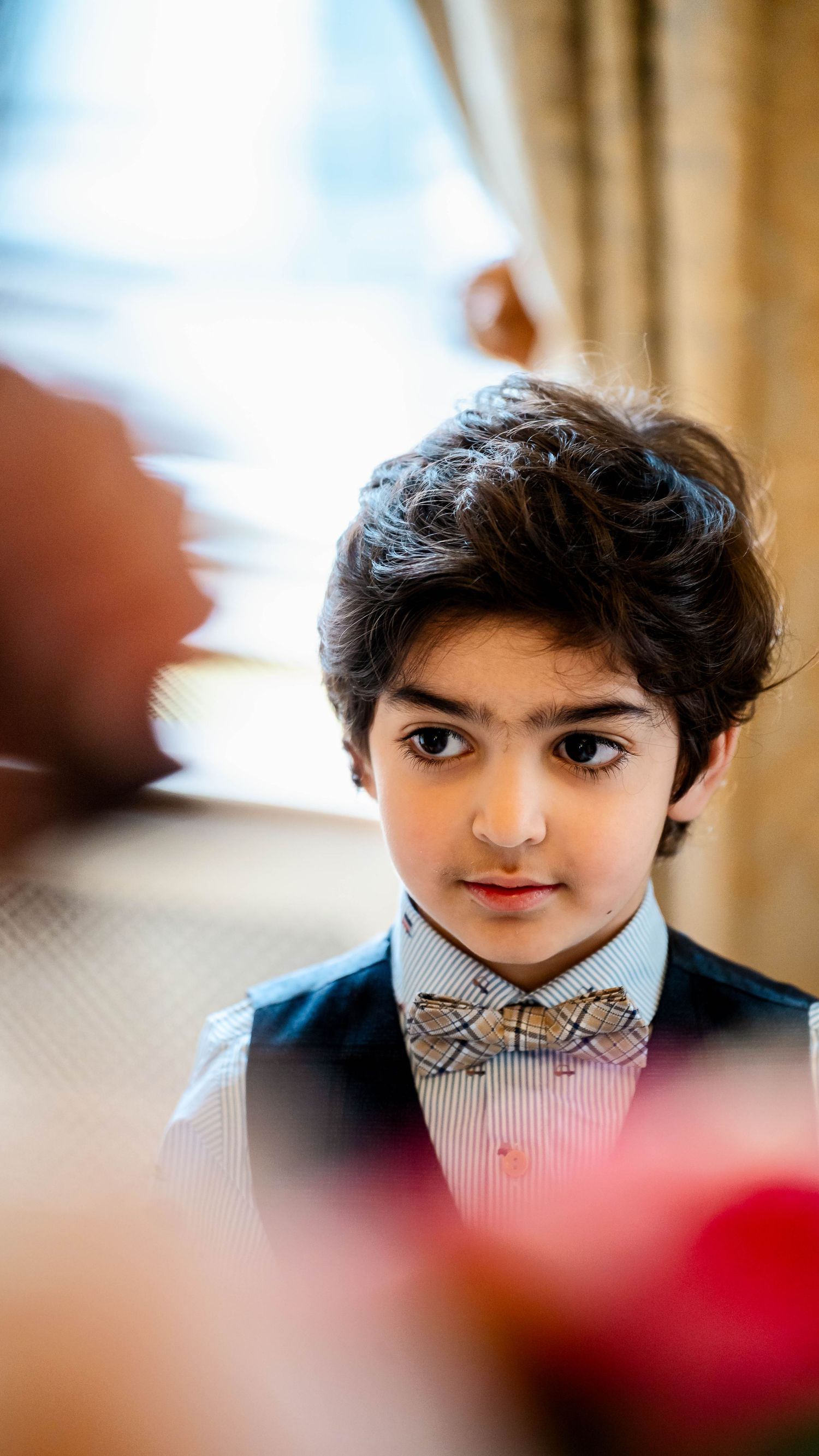 A young ring bearer in a formal suit and bowtie at a wedding ceremony.