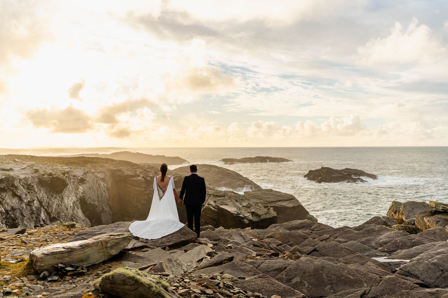 Dramatic coastal landscape with rocky cliffs and ocean waves at sunset.