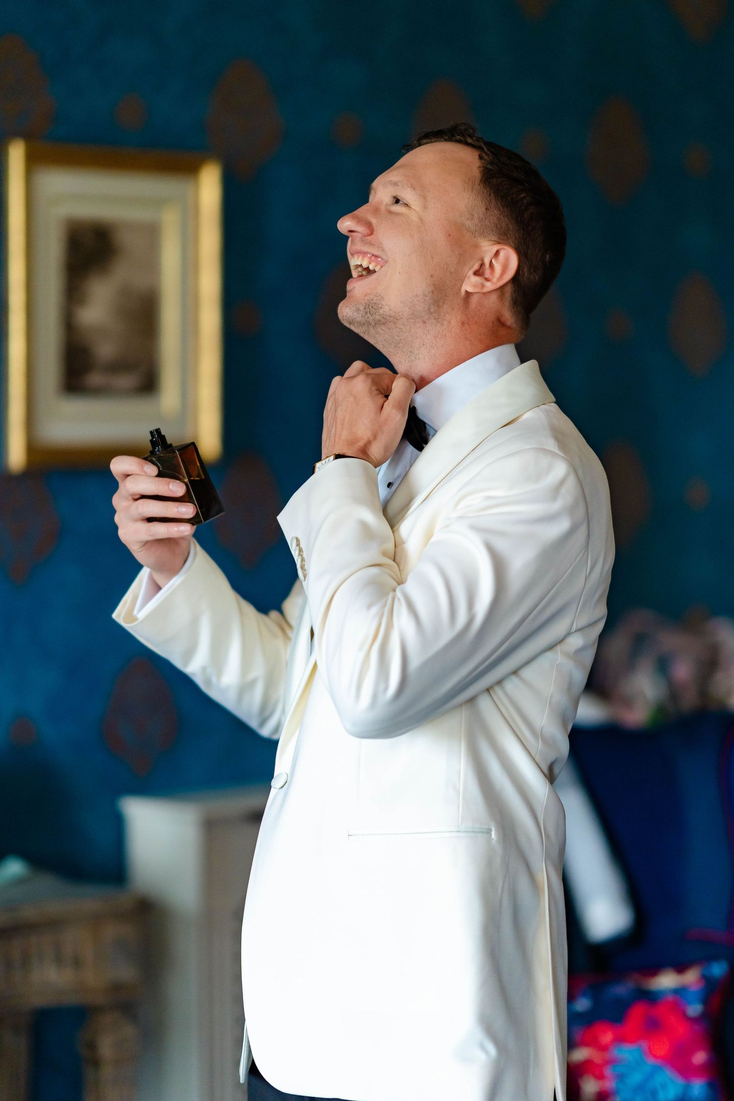 Person in white dress shirt laughs and gestures while speaking into microphone during indoor performance.