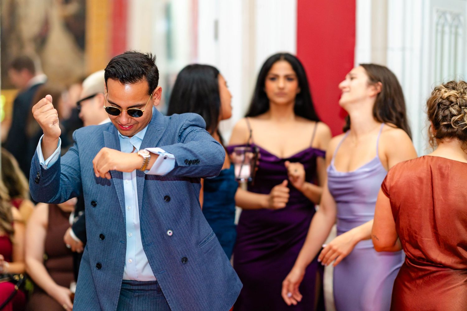 People dancing and celebrating at an elegant party with someone in a blue suit doing a dance move.