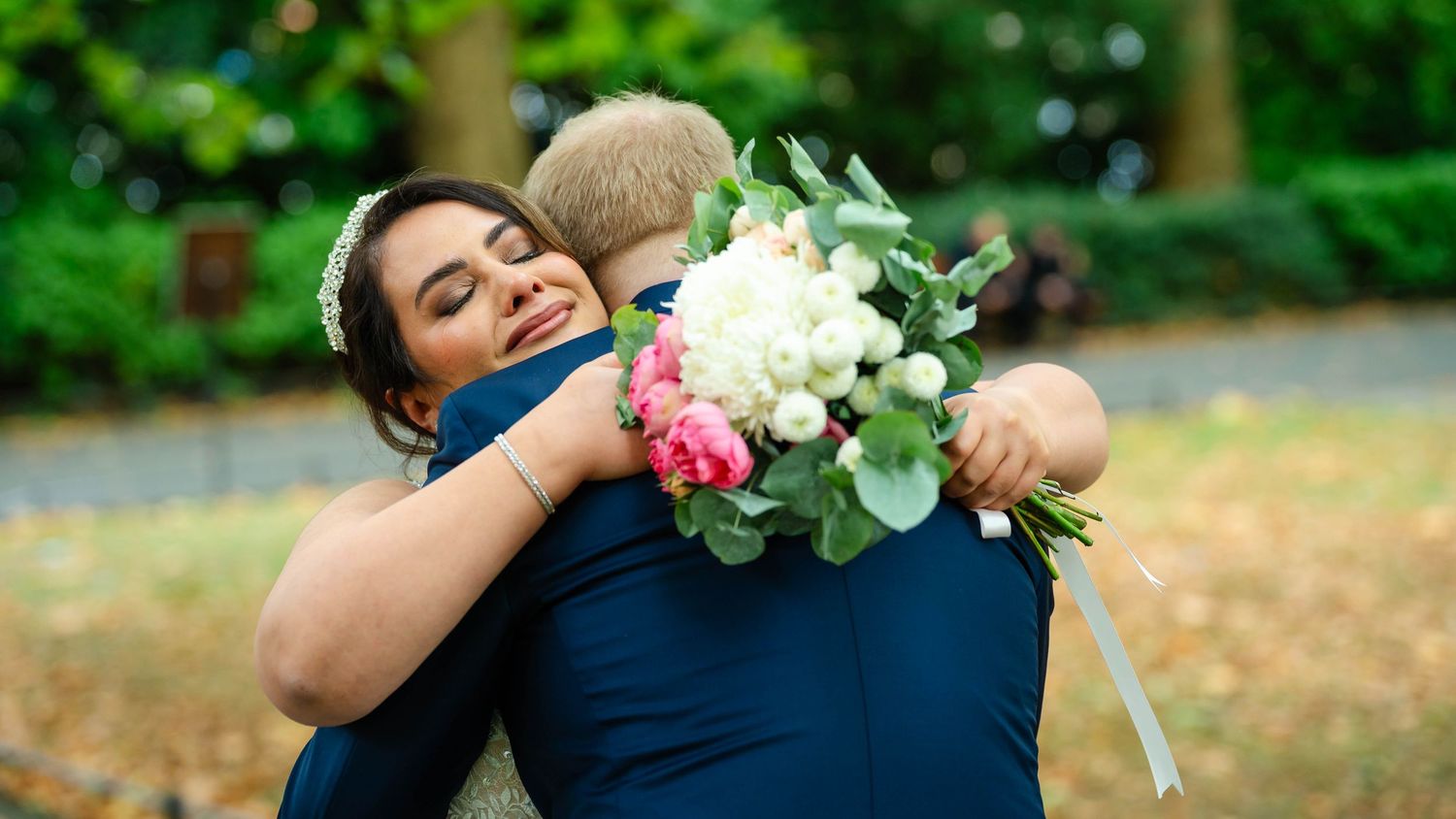 Romantic first look moment captured in panoramic style on a park pathway.
