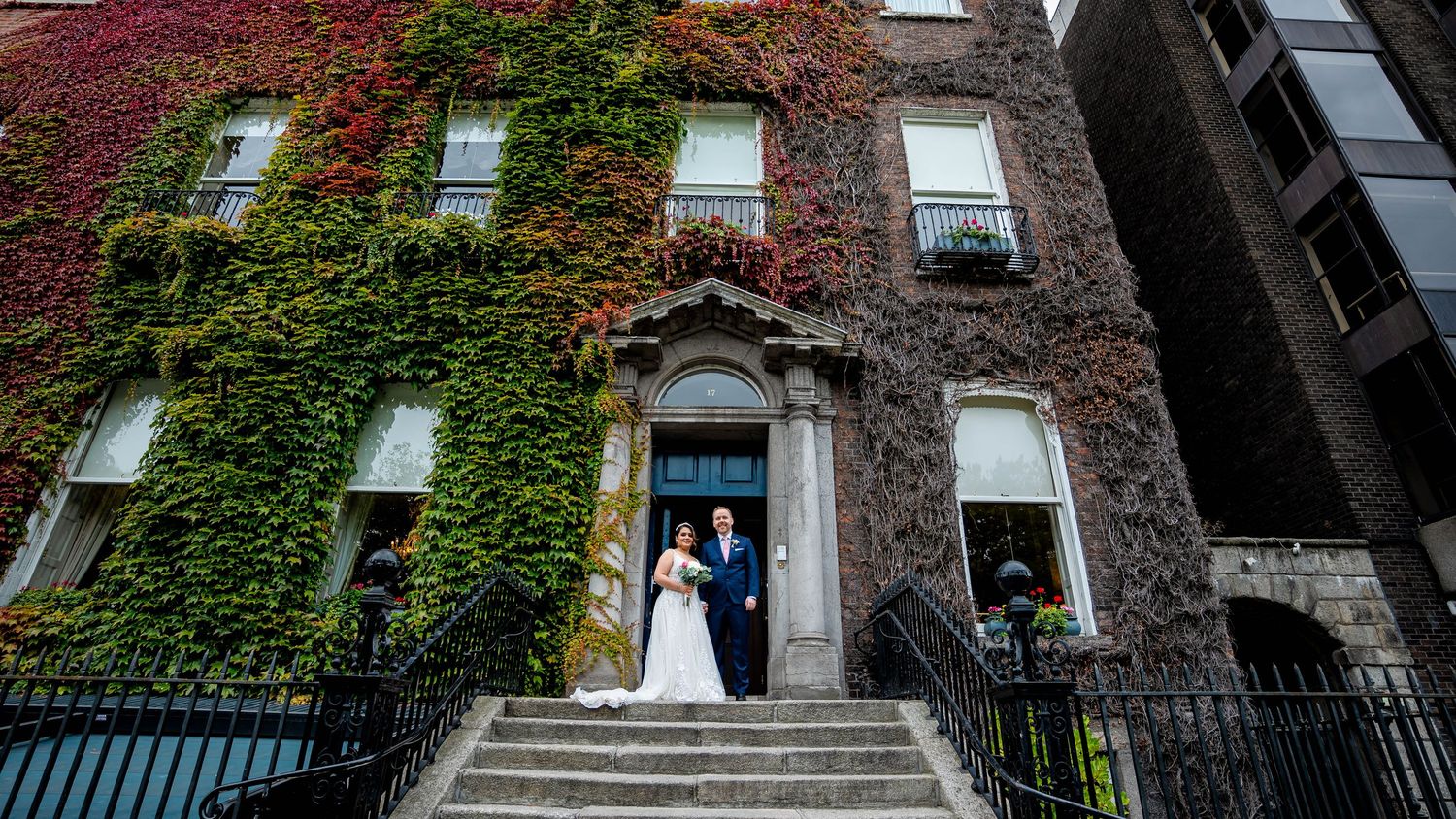 Panoramic view of an ivy-covered stone building with multiple windows.