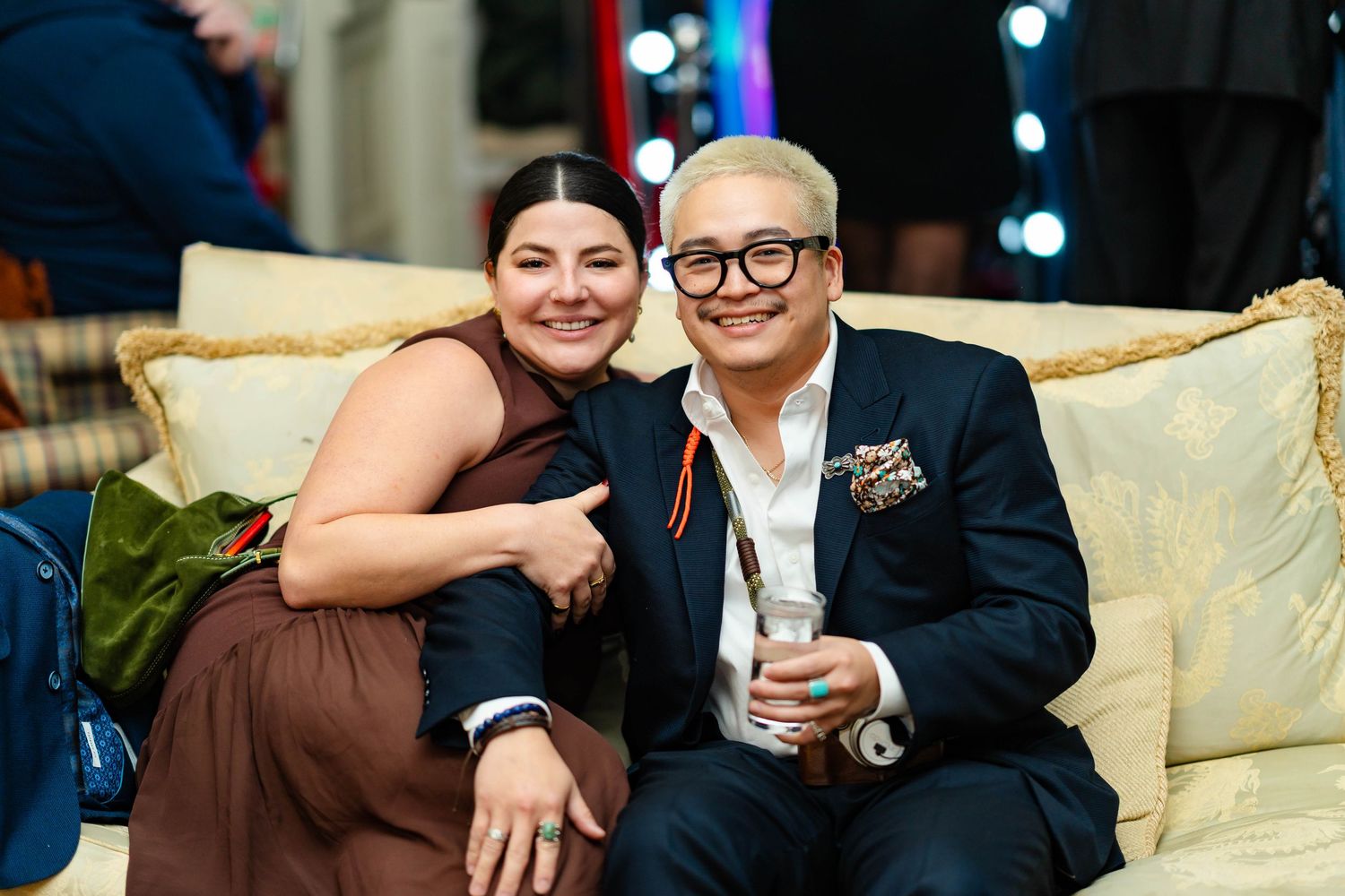 A couple shares a tender moment during their wedding celebration with blurred lights in the background.