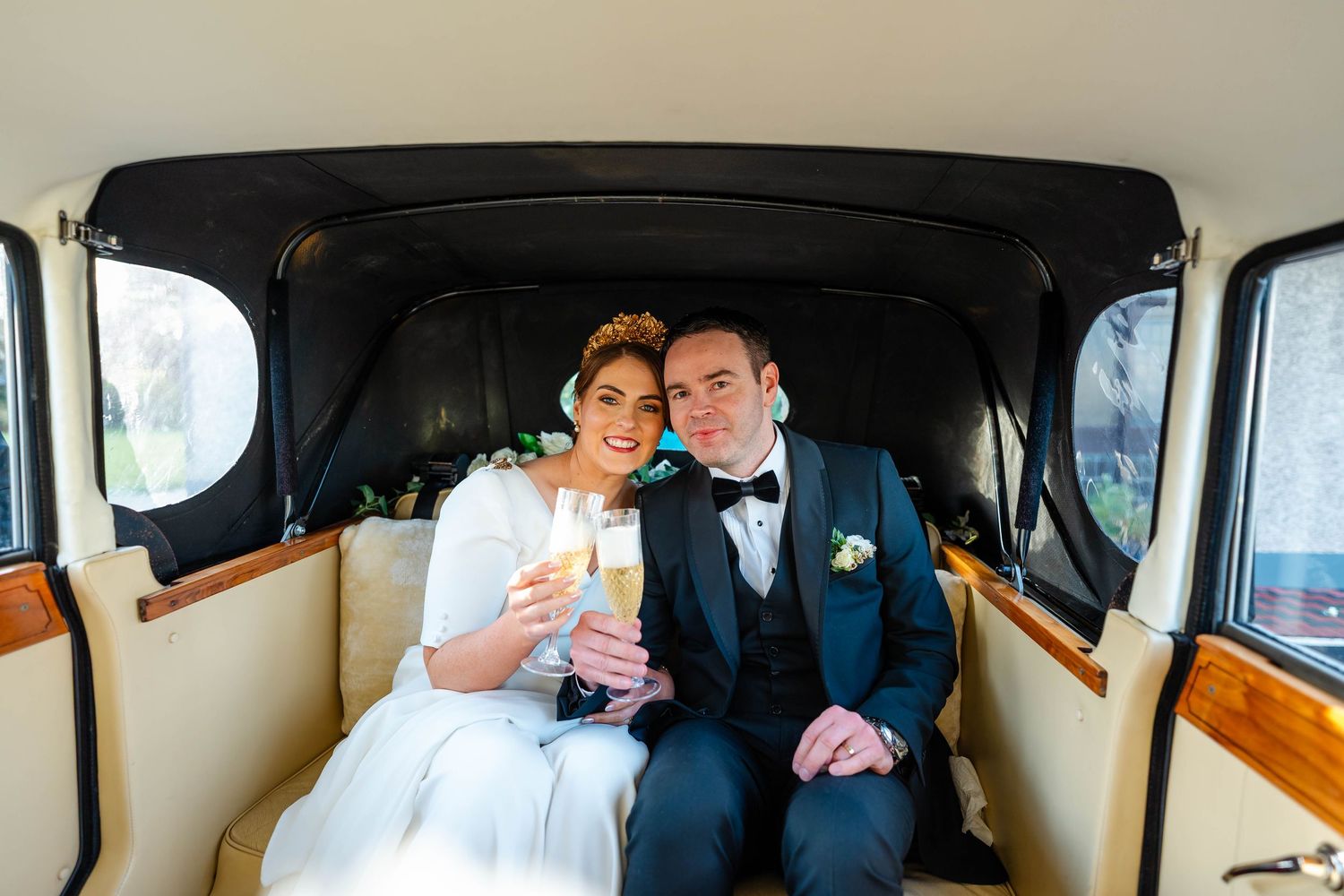 Newlyweds sharing drinks and intimate moments inside classic car.