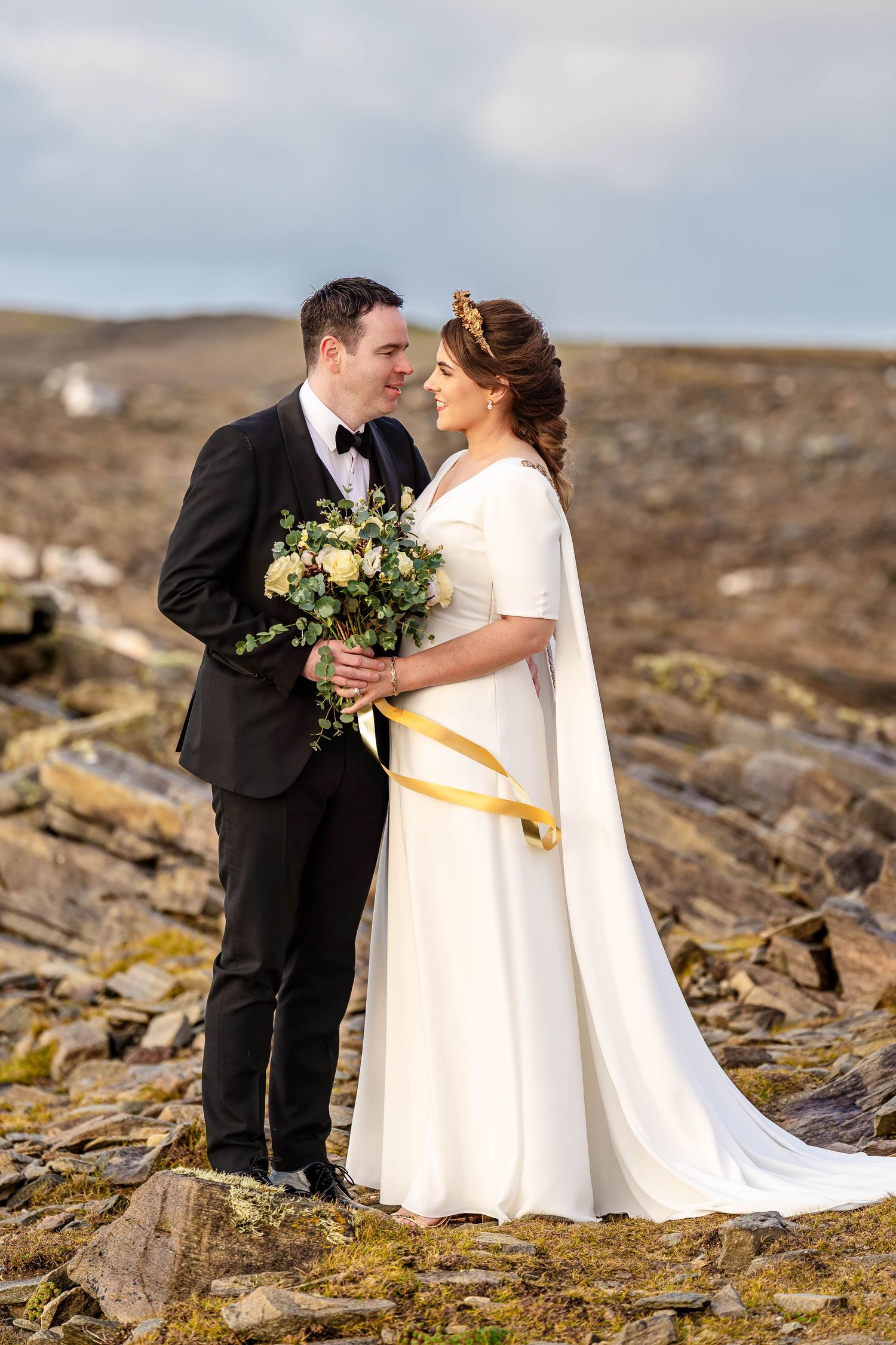Newlyweds share an intimate moment on rugged coastal cliffs during their wedding.