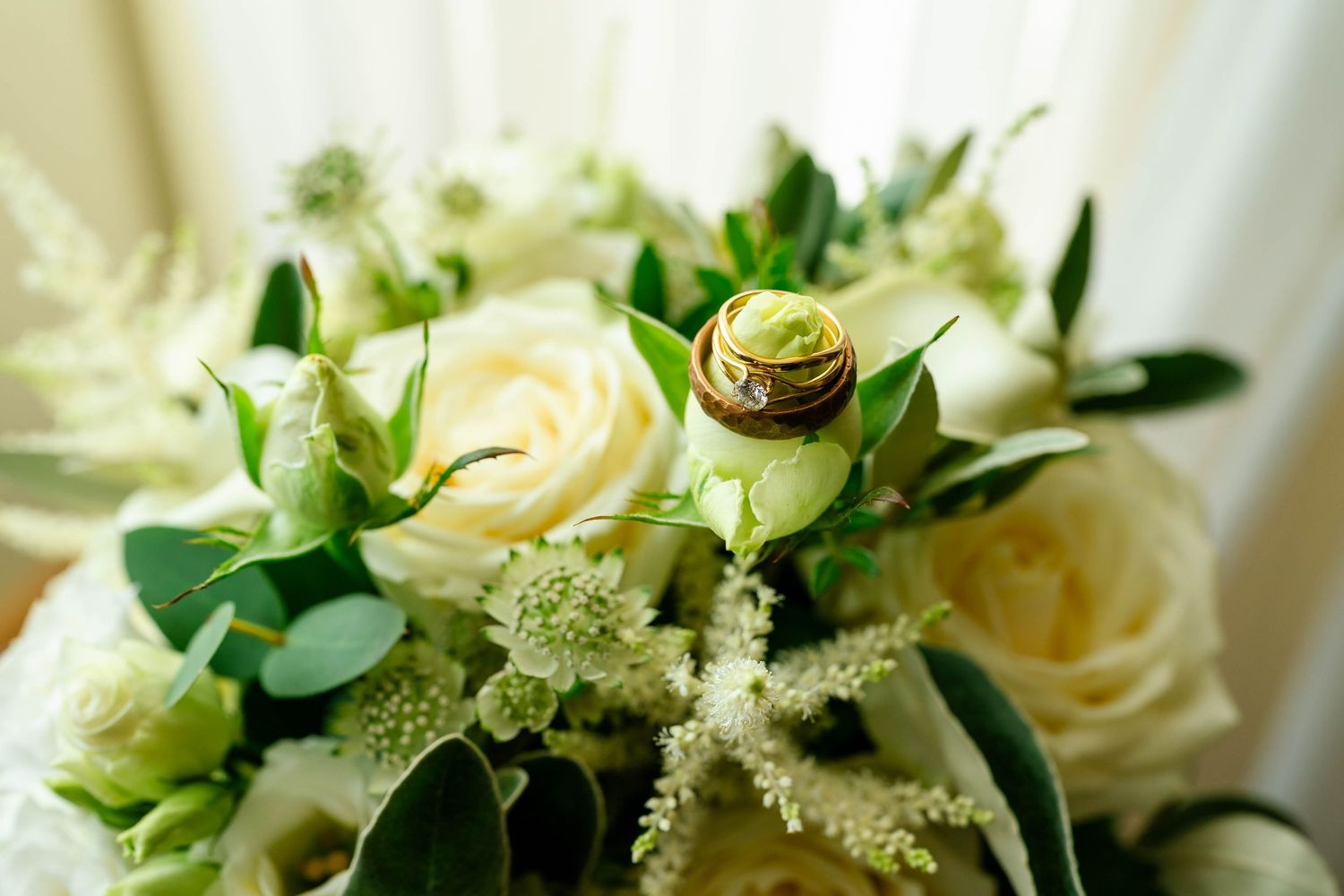 Close-up of cream roses and delicate white floral arrangements with green foliage.