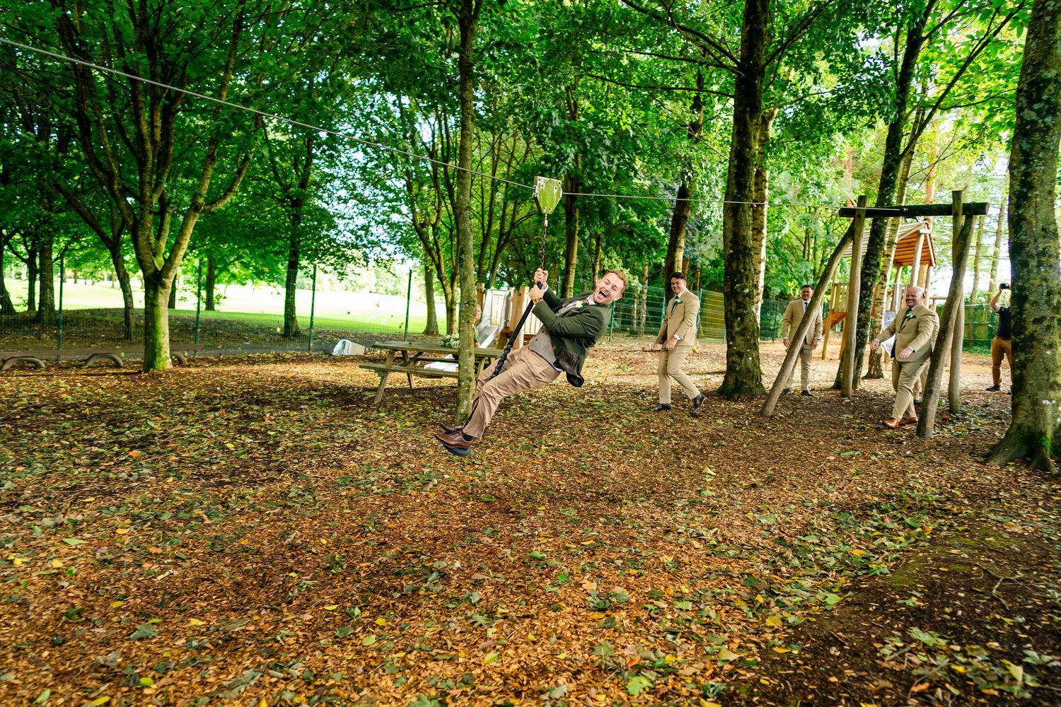 Natural woodland walking trail surrounded by tall trees and scattered autumn leaves.