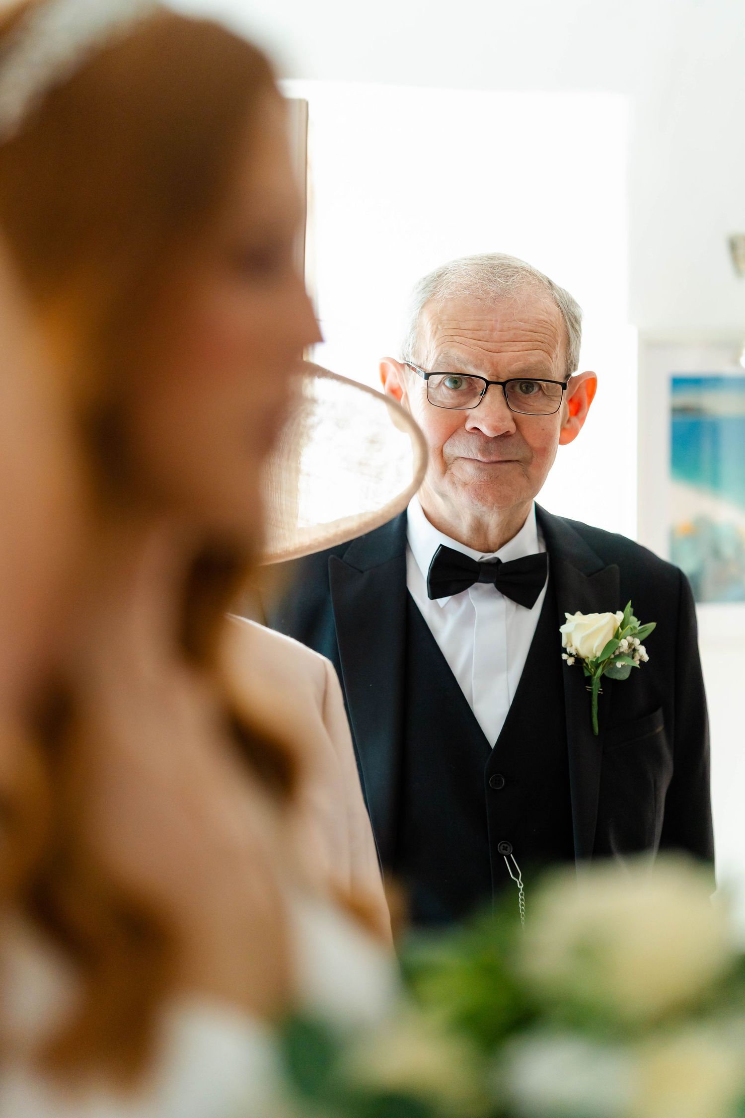 Elegant gentleman in a black tuxedo and bowtie with boutonniere at formal event.