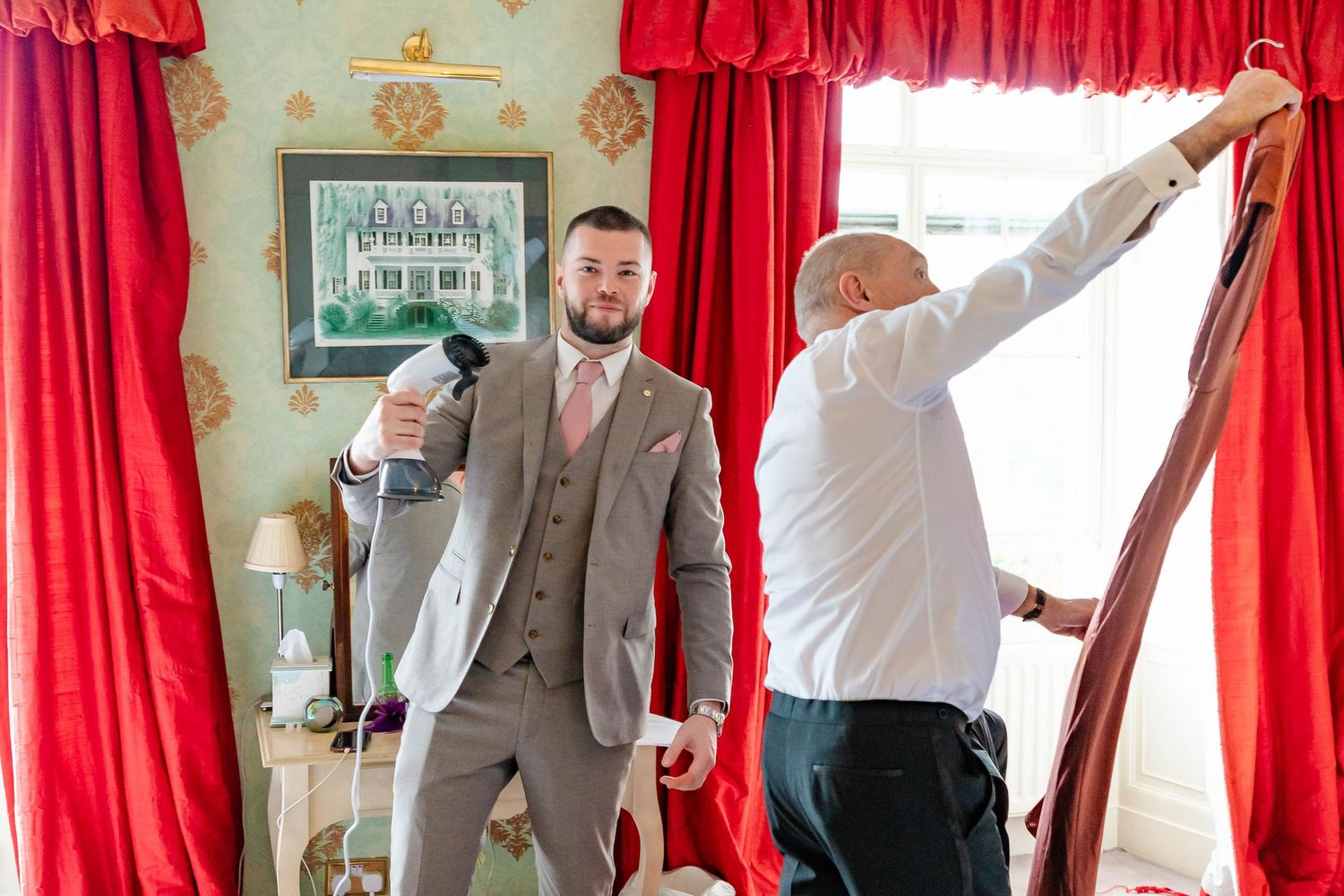 Wedding party members pull red curtain cords to reveal something during a celebratory unveiling moment.