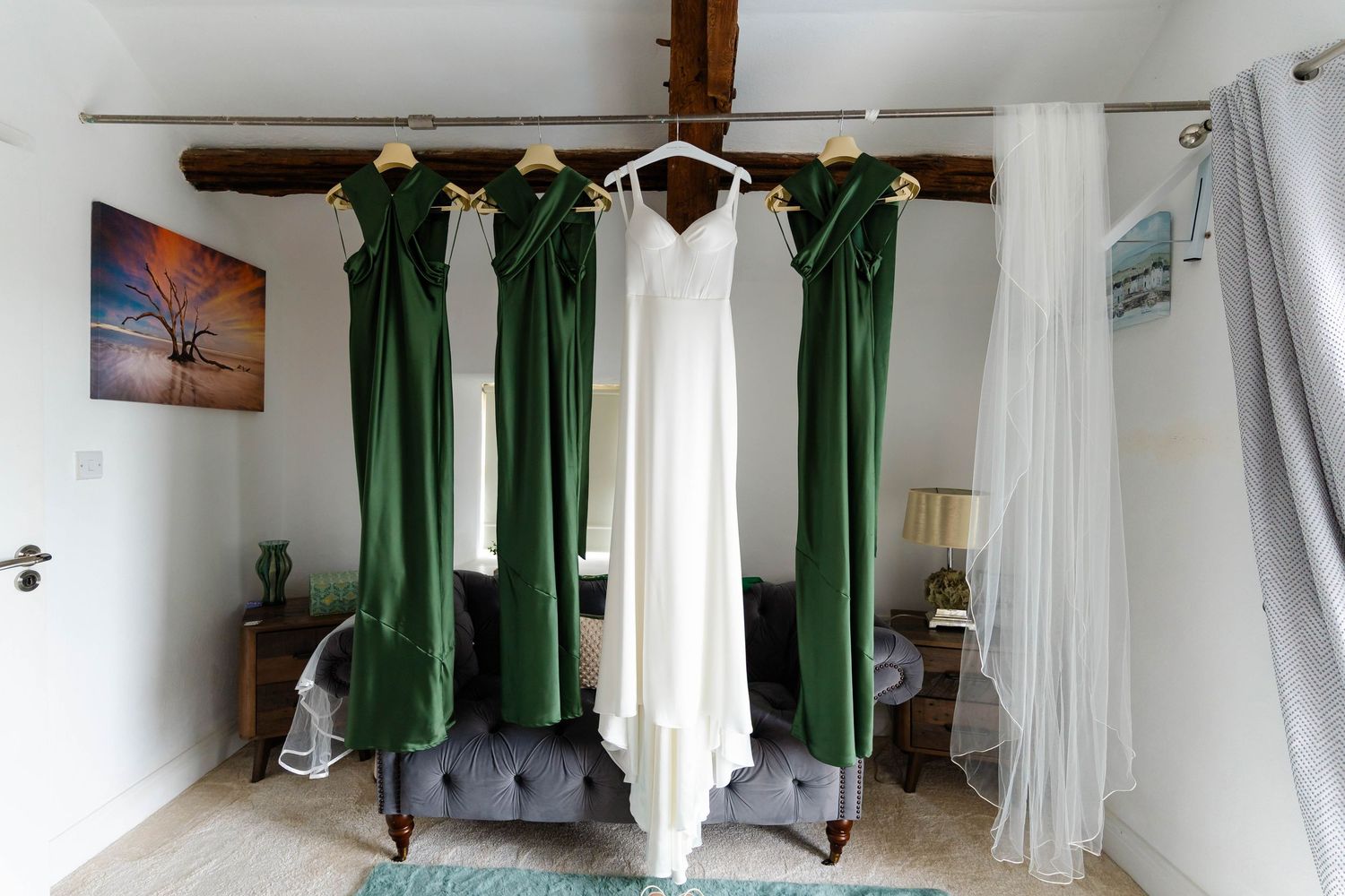 Interior room with green curtains and white drapes hanging from wooden beams.