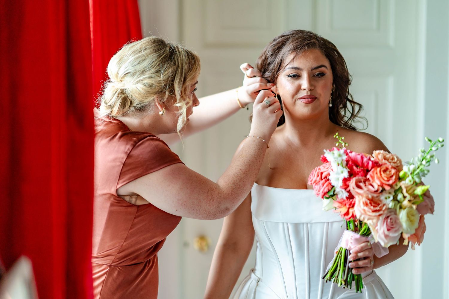 Final touches being made to bridal preparations with a beautiful bouquet of coral and pink flowers.