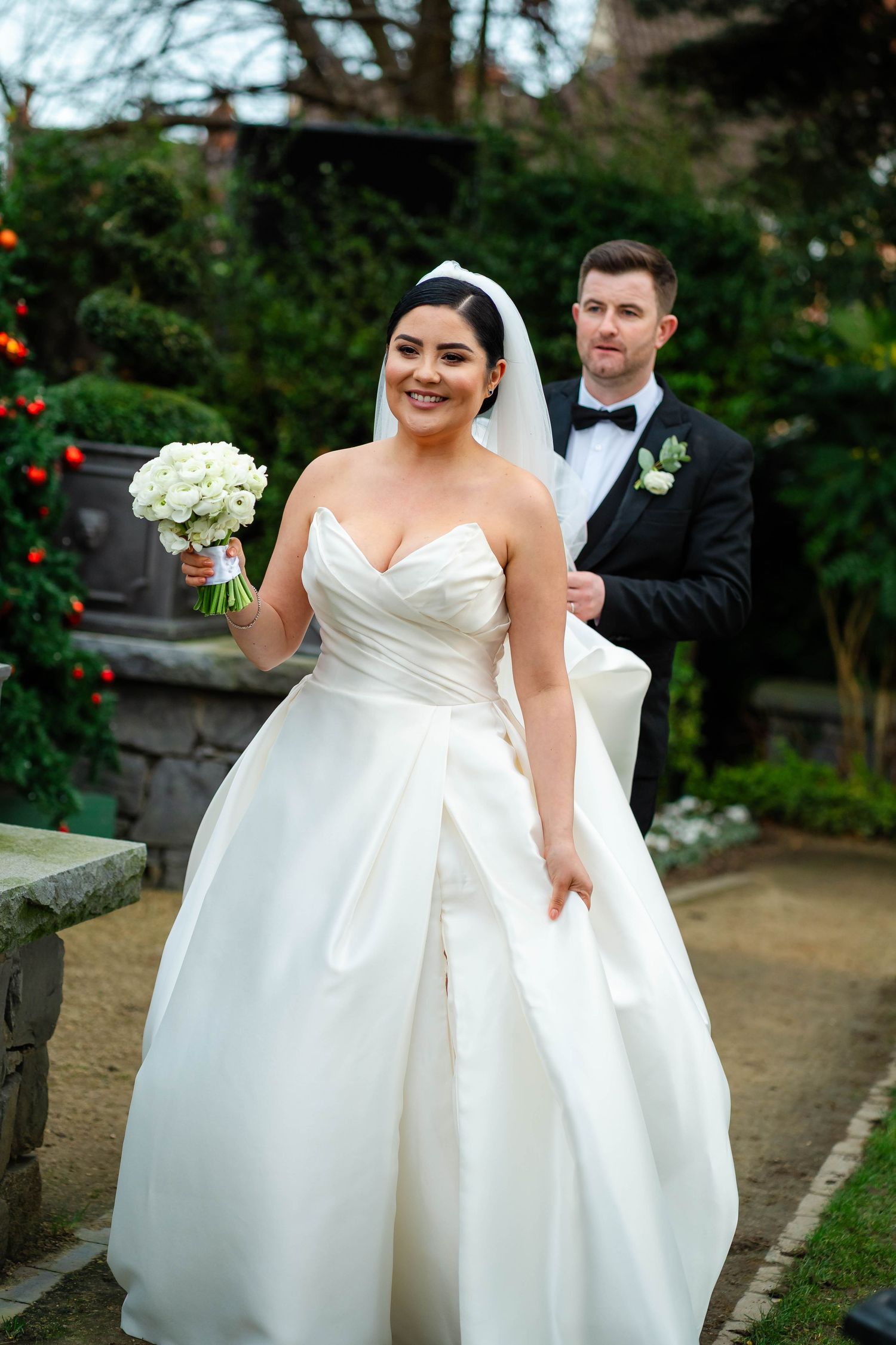 Wedding couple laughs together as bride's white dress billows in the breeze.