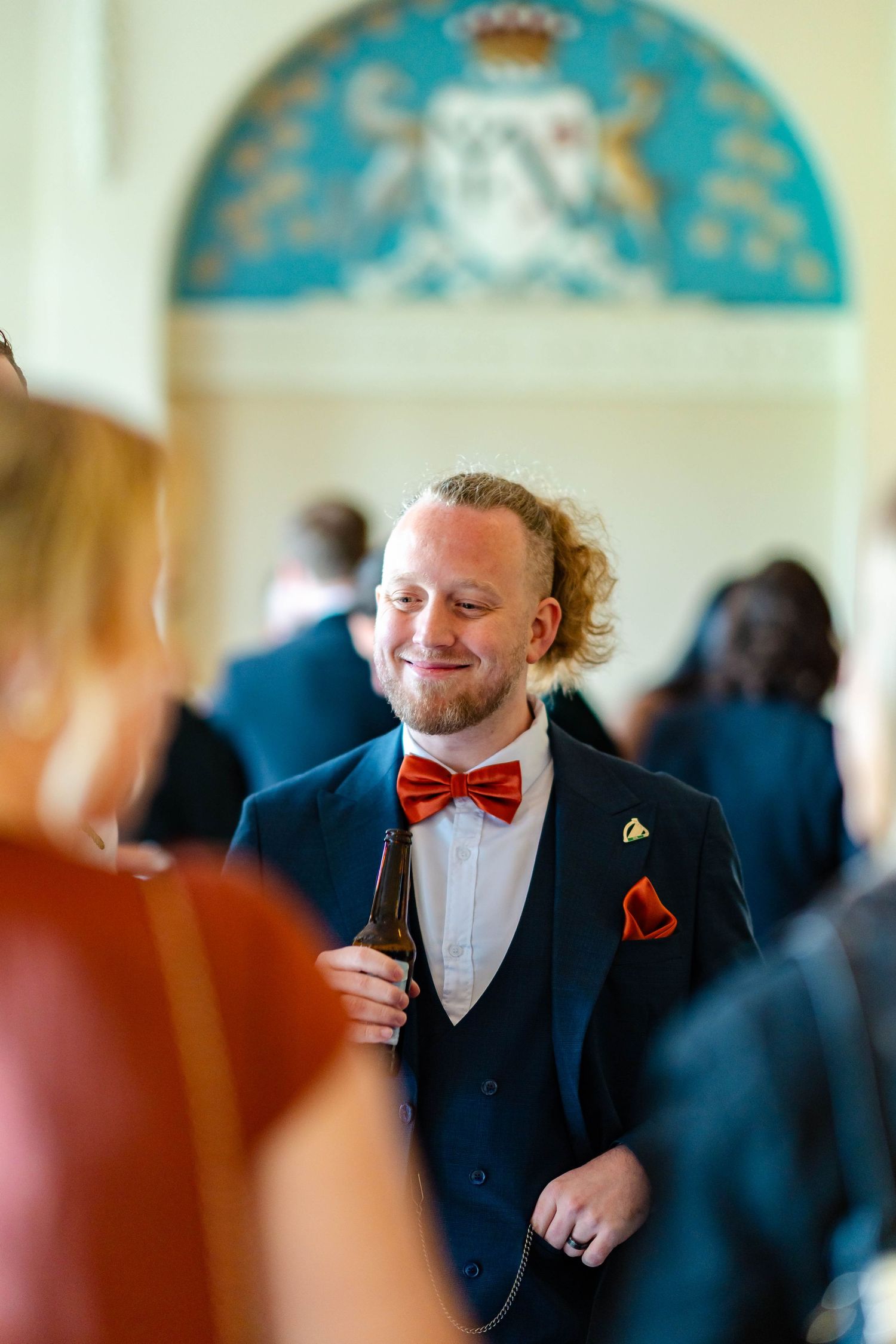 Groomsmen in navy suits with red bow ties celebrate at an elegant wedding venue.