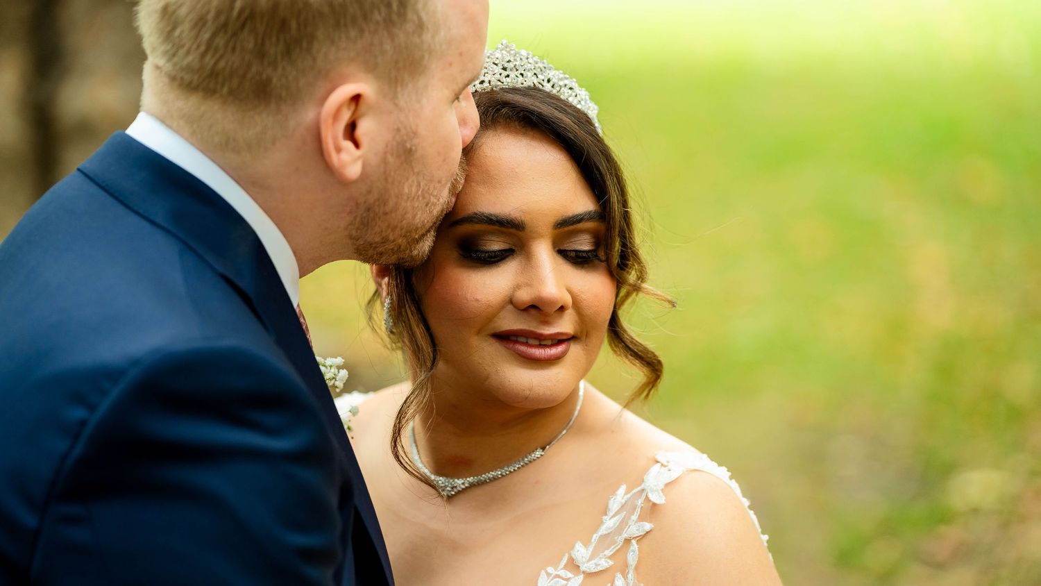 A romantic wedding couple shares tender moments in a garden setting.