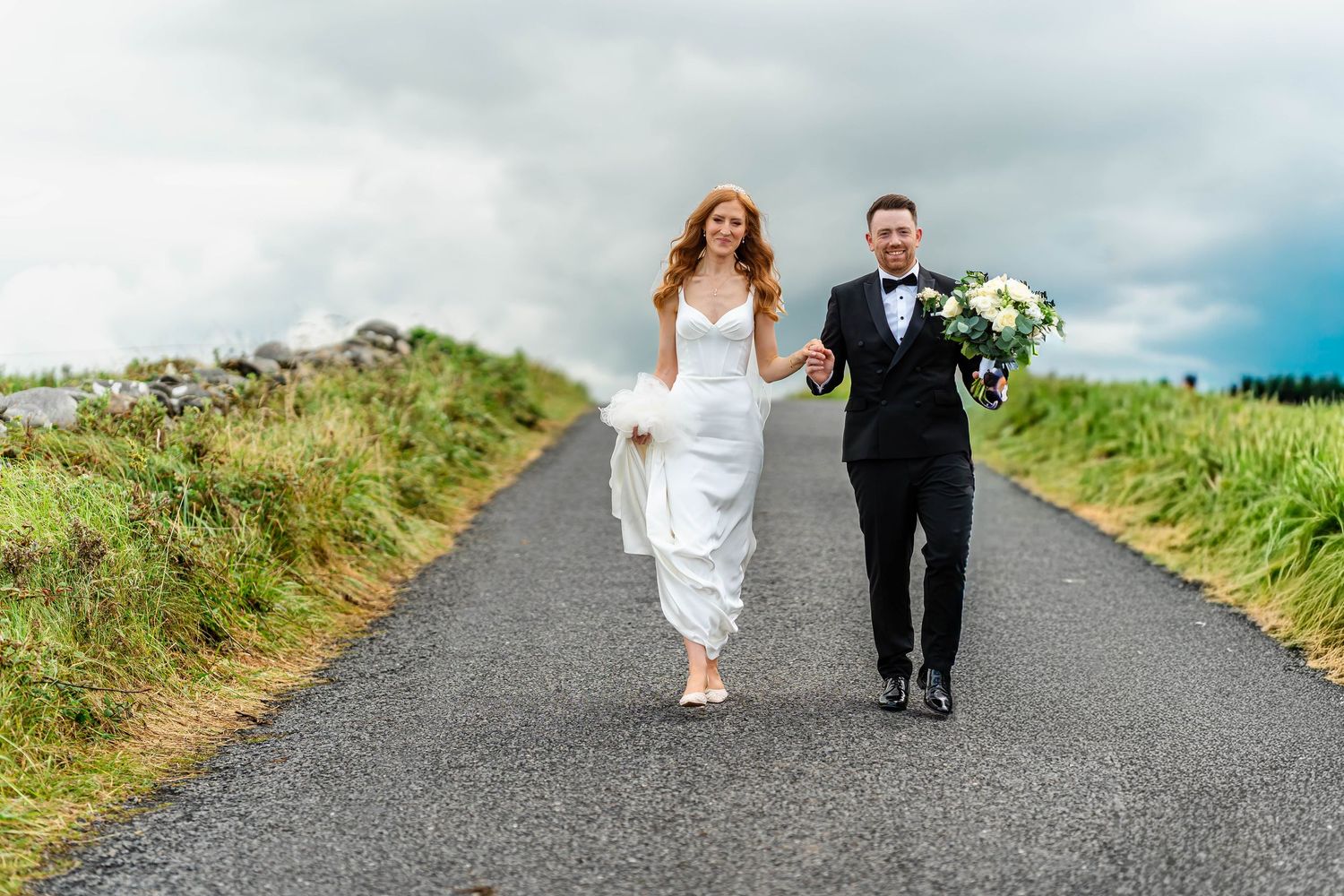 Newlyweds walk together down a scenic coastal path during their destination wedding.