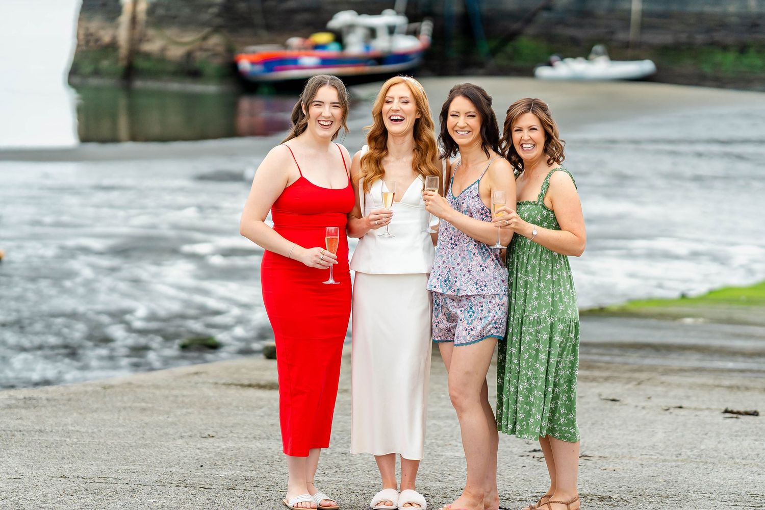 Friends in colorful dresses share a moment together by the harbor.