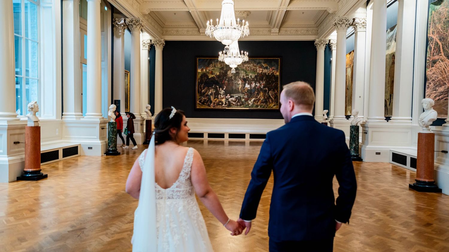 Elegant ballroom with crystal chandeliers and ornate white columns creates a grand wedding venue atmosphere.