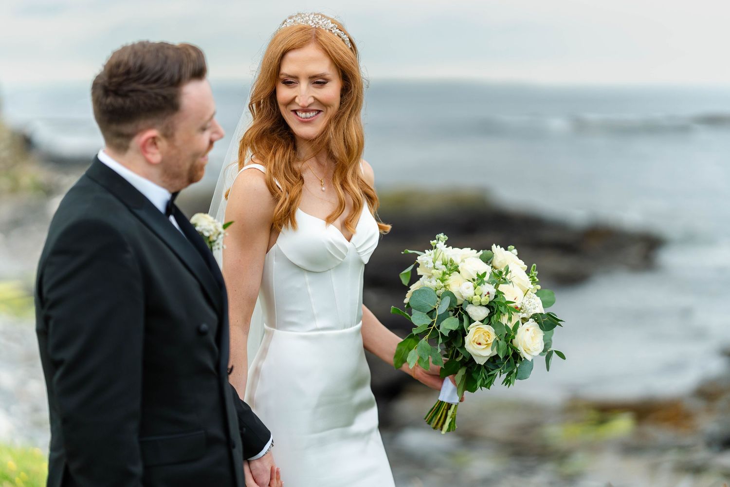 Intimate wedding moment captured against dramatic coastal scenery.