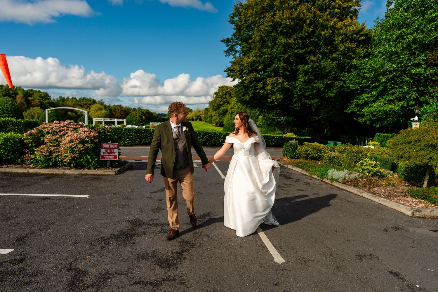 Wedding couple and guests walking through parking area after ceremony.