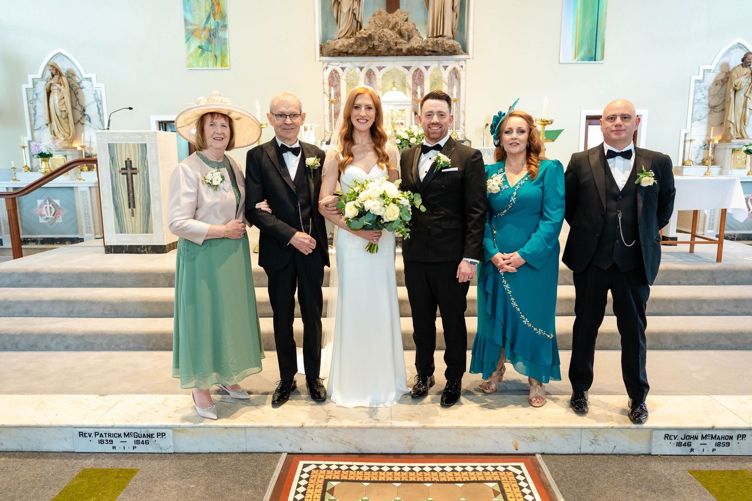 Wedding party members lined up inside church sanctuary with religious artwork.