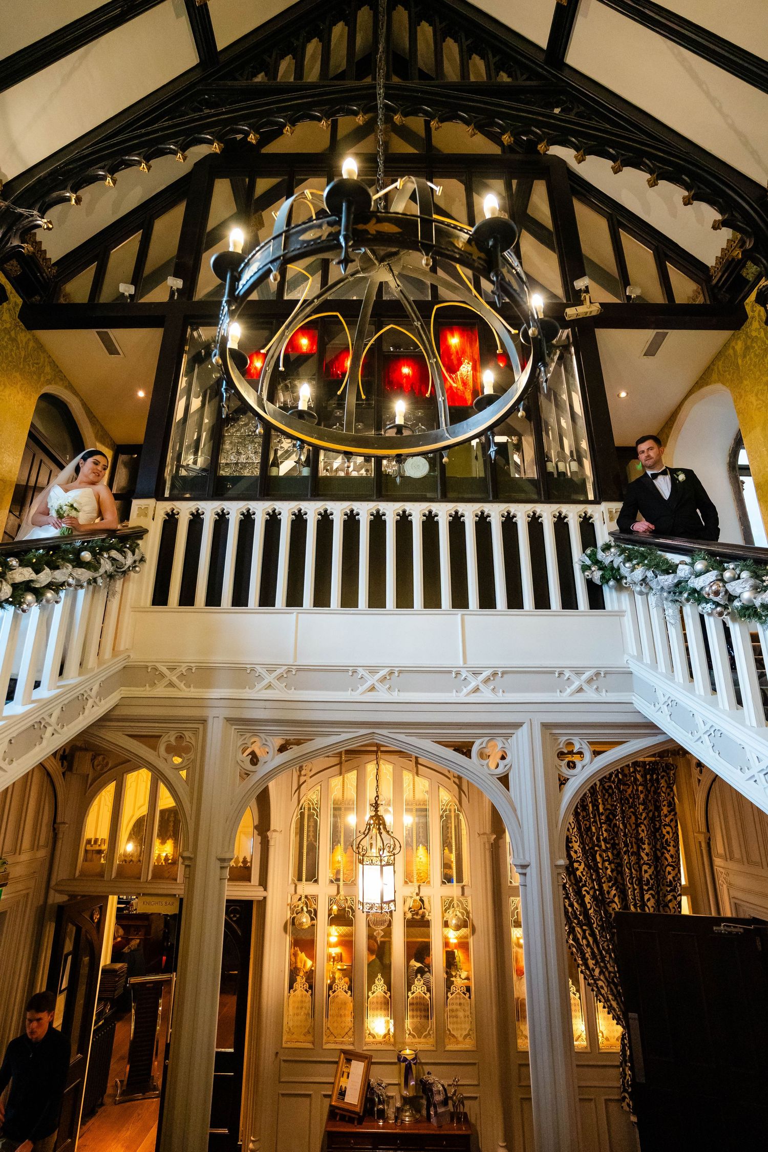 An elegant wedding venue interior with chandelier, white railings, and holiday decorations.