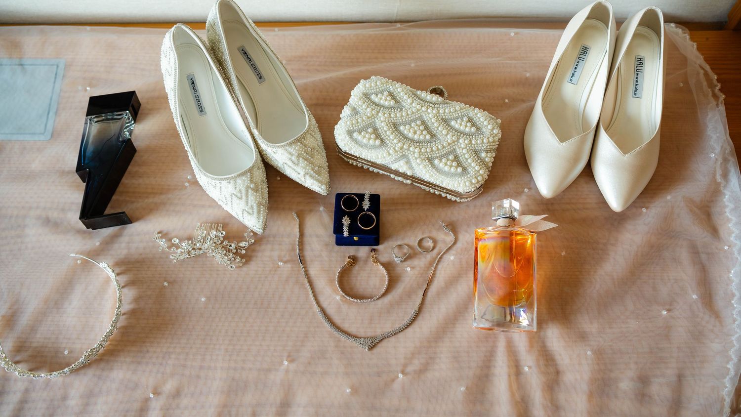 Flat lay of bridal accessories including white heels and delicate lace details.
