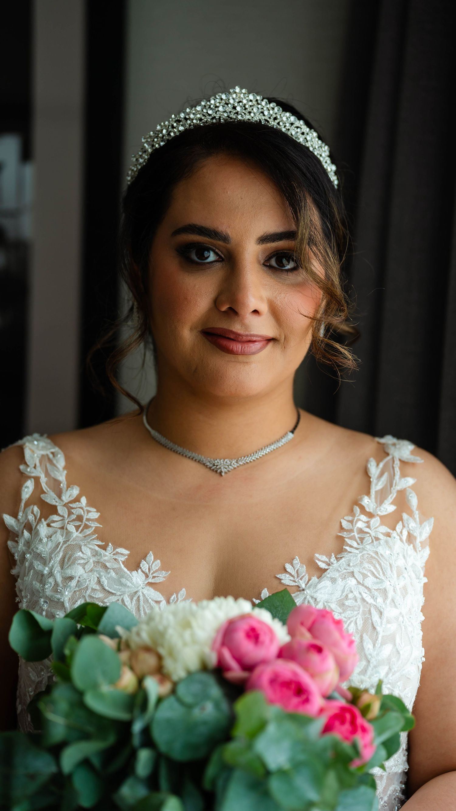 Bride holding a bouquet featuring pink roses and eucalyptus leaves.