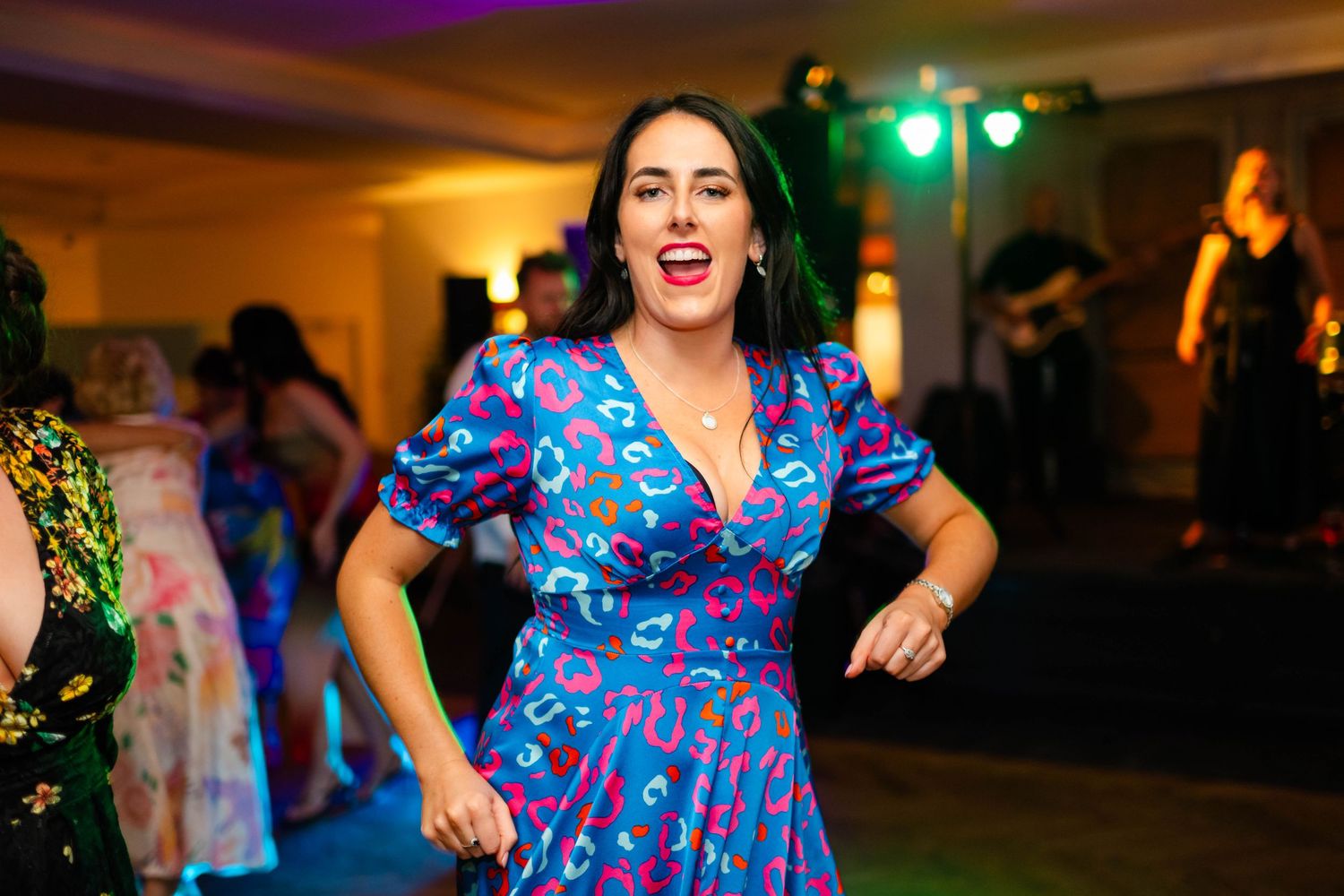 Guests in colorful attire dancing enthusiastically at an evening wedding reception.