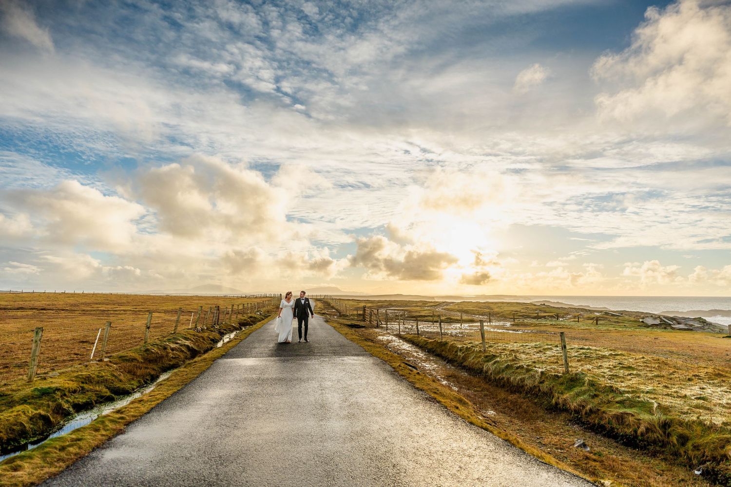 Long winding road through misty countryside with dramatic cloudy sky at sunset.