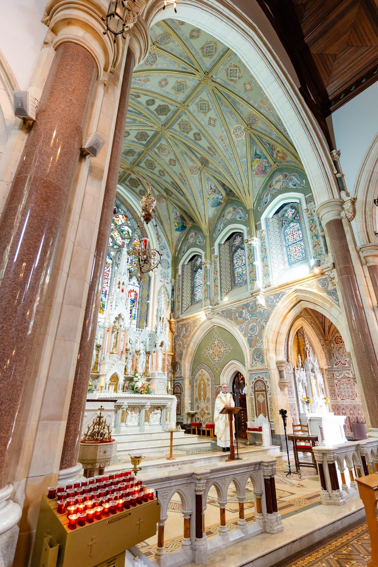 Interior view of an ornate cathedral with arched ceilings, stained glass windows, and decorative architectural details.