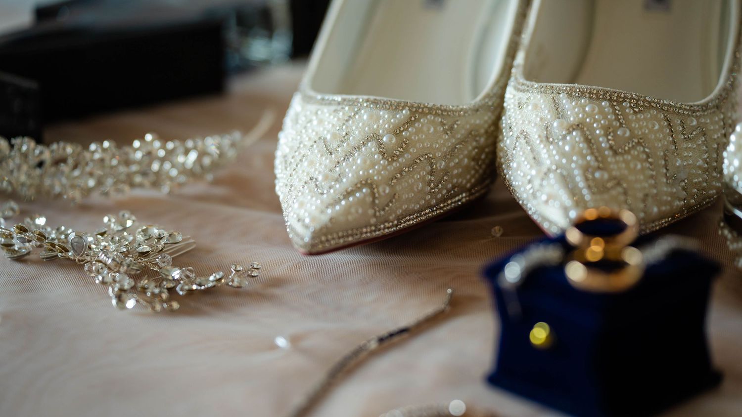 Wedding accessories including sparkly shoes and delicate jewelry arranged on a light surface.