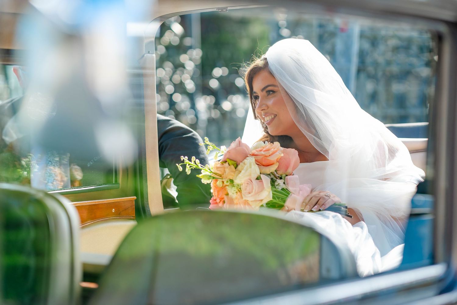 A wedding couple sits together in the back of a car looking out the window on their special day.