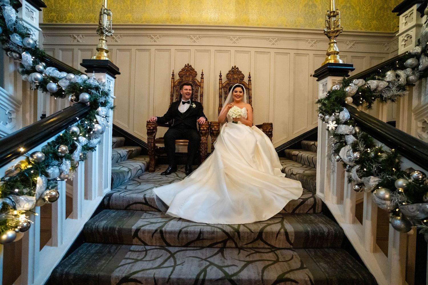 A flowing white wedding gown displayed on a grand staircase with festive Christmas decorations.