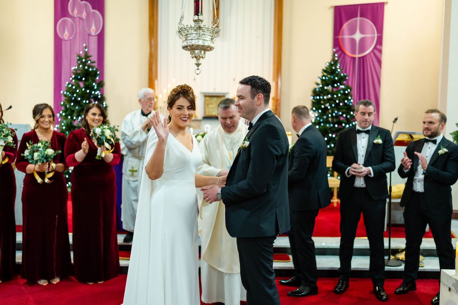 Church altar decorated with purple banners and Christmas trees during a wedding ceremony.