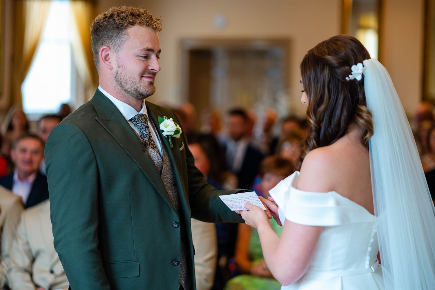 Couple exchanges vows during their wedding ceremony while guests look on.