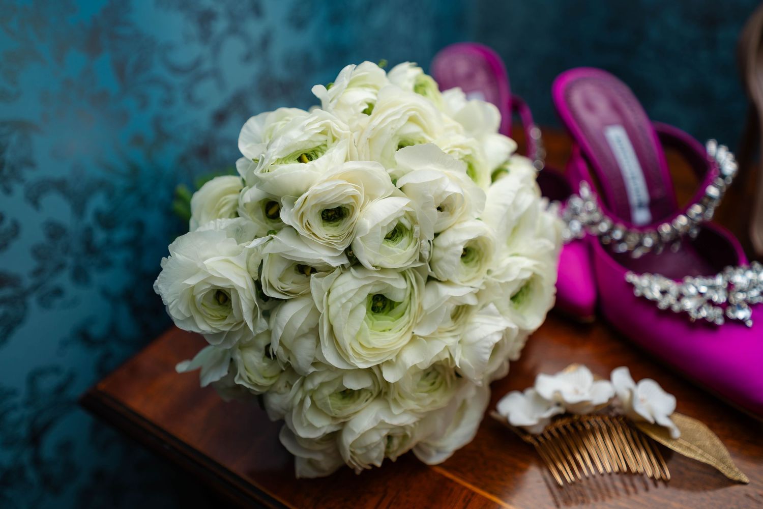 White ranunculus bridal bouquet with wedding accessories on display.