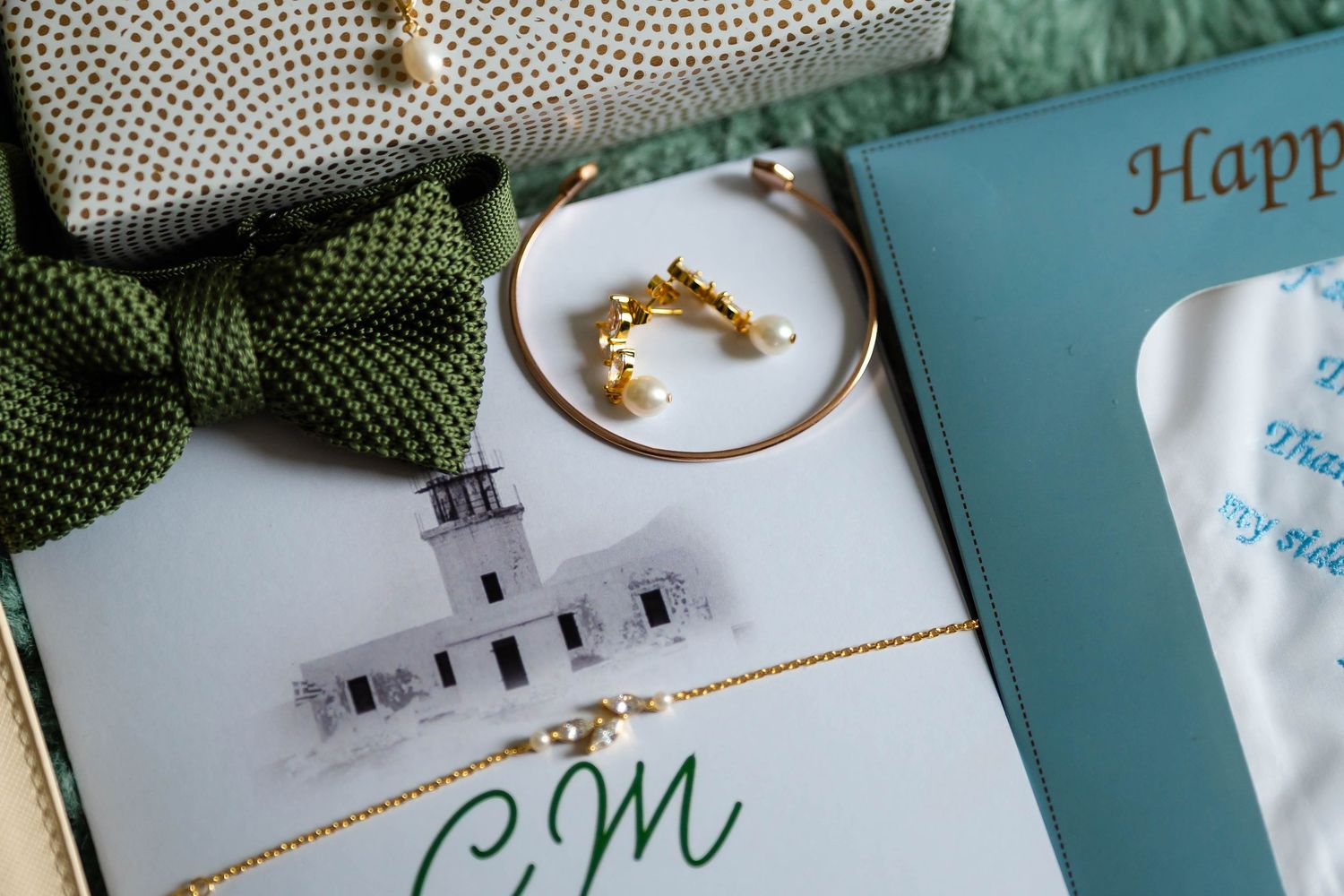 Wedding stationery and accessories arranged on turquoise background with gold accents.