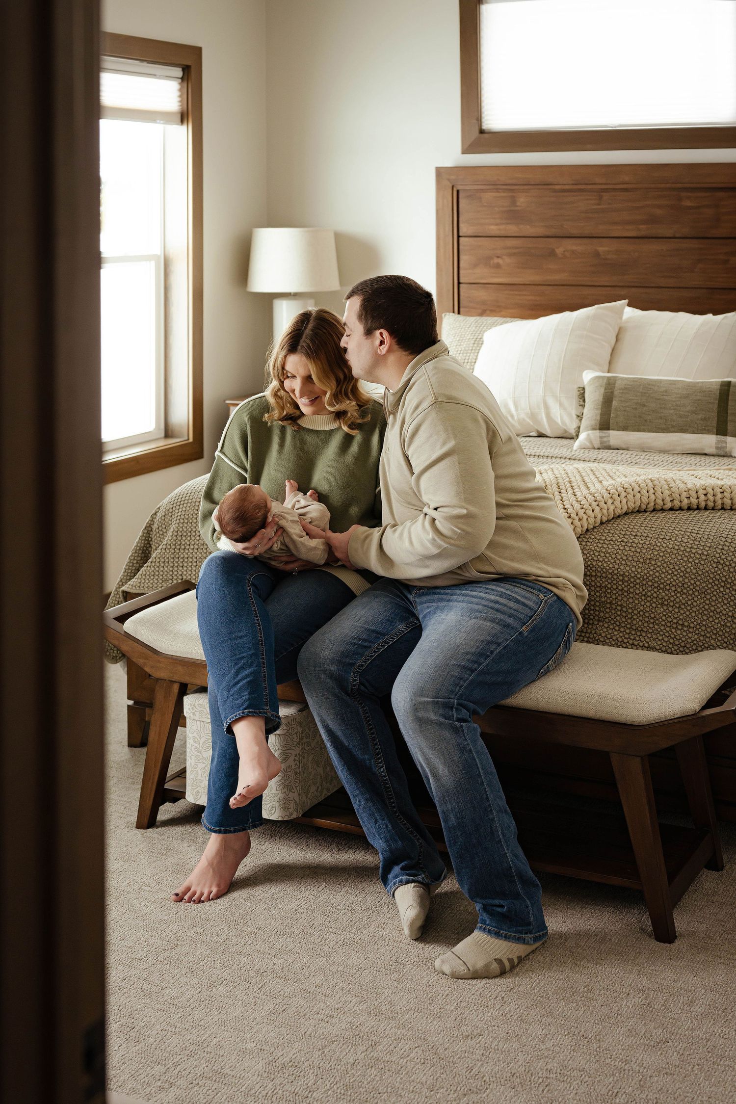 A tender moment captured in a bedroom with people sitting together on a modern wooden bed frame.