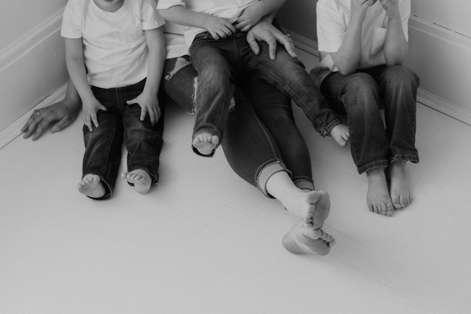 A series of black and white photographs showing feet and legs of people sitting against a wall.