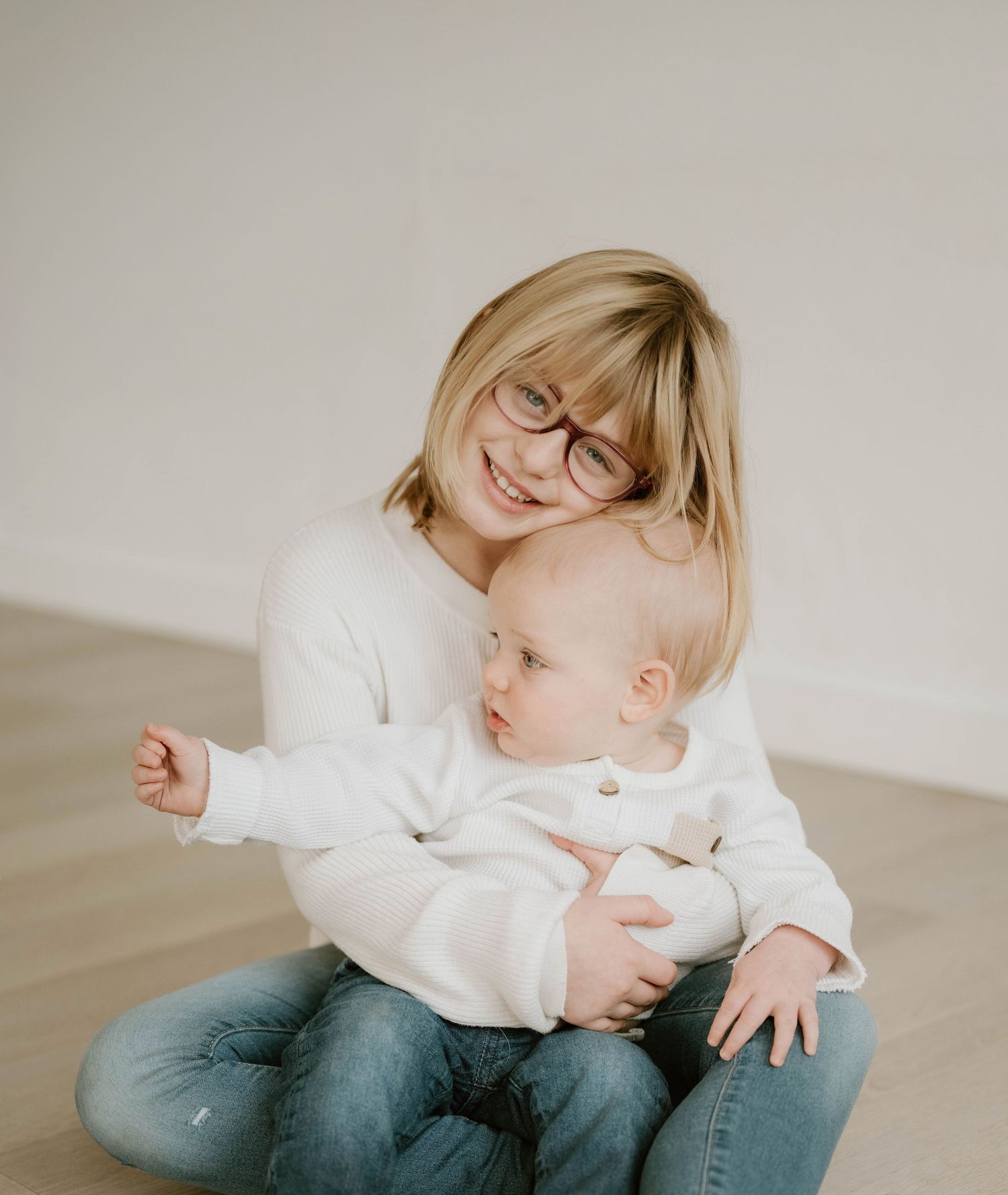 A sequence of photos showing a child in white sweater and jeans playfully rolling on a light colored floor.