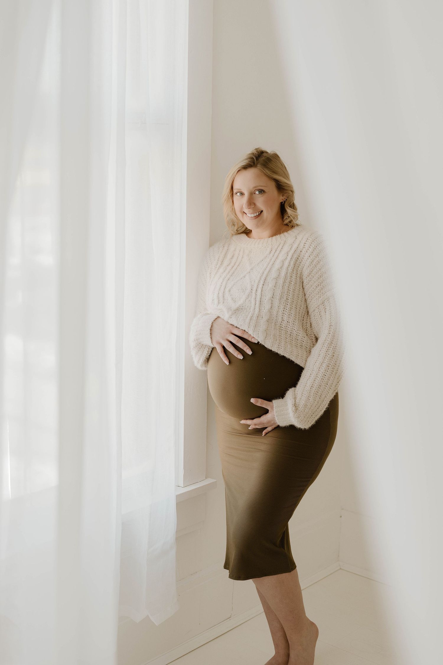 A series of maternity photos showing a pregnant woman in a cream sweater and brown skirt against a light background.